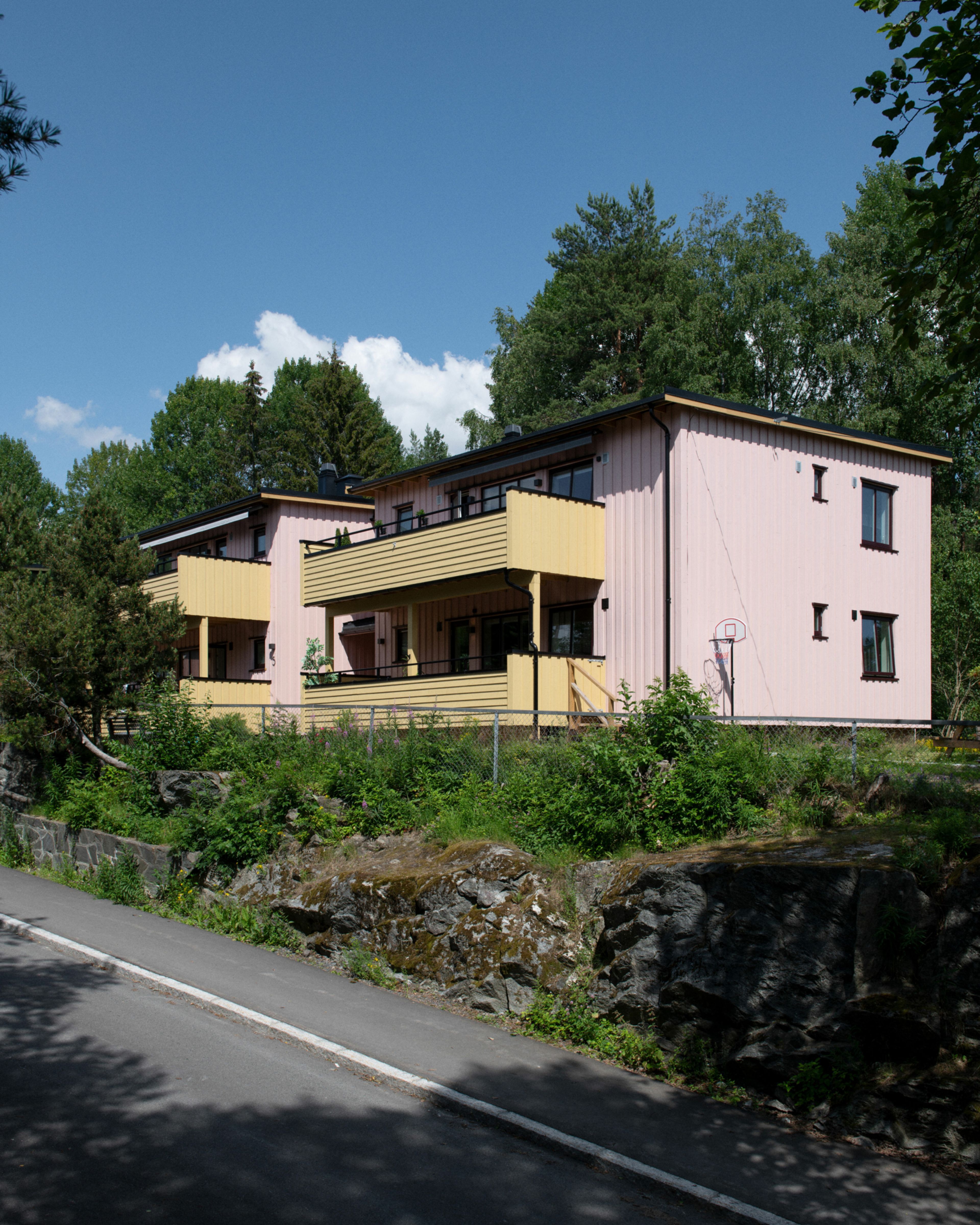 Et hus med rosa fasade og gule balkonger i et av rekkehusene i Beverdalen Borettslag.