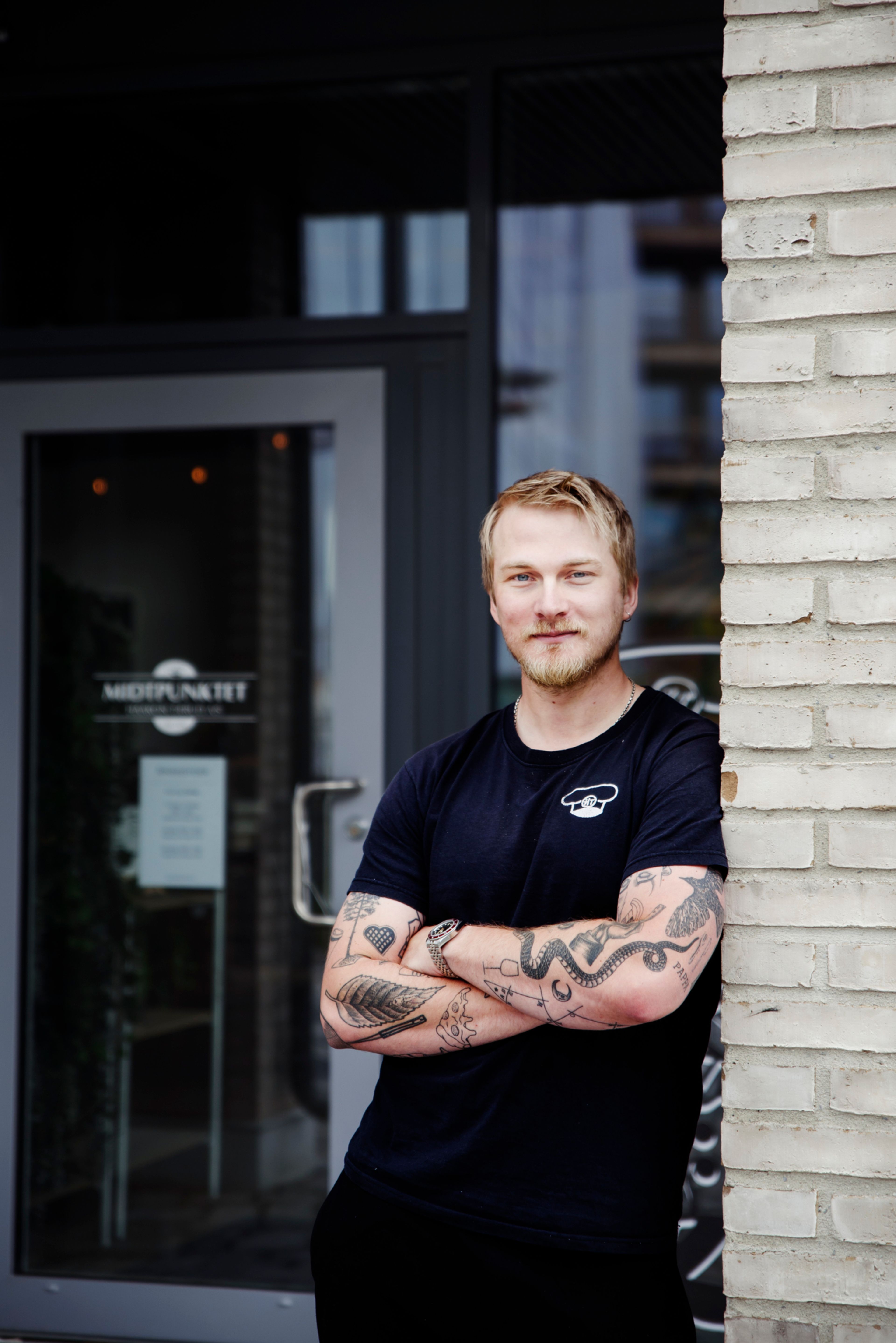 Martin Tærud står lent inntil en mursteinsvegg