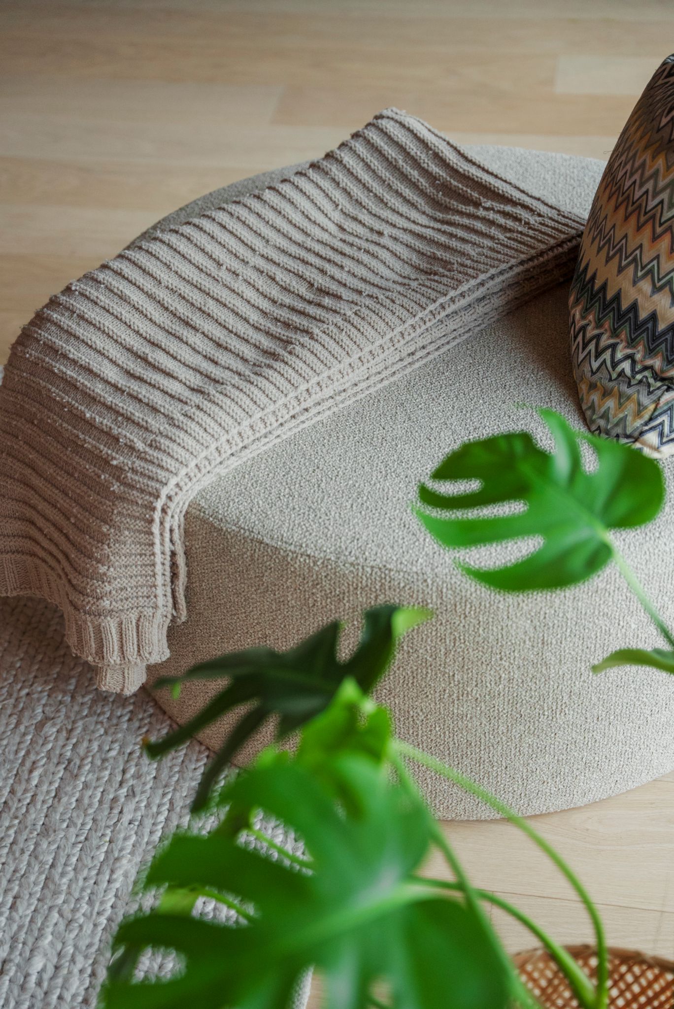 Detaljbilde av en beige puff med et beige pledd over