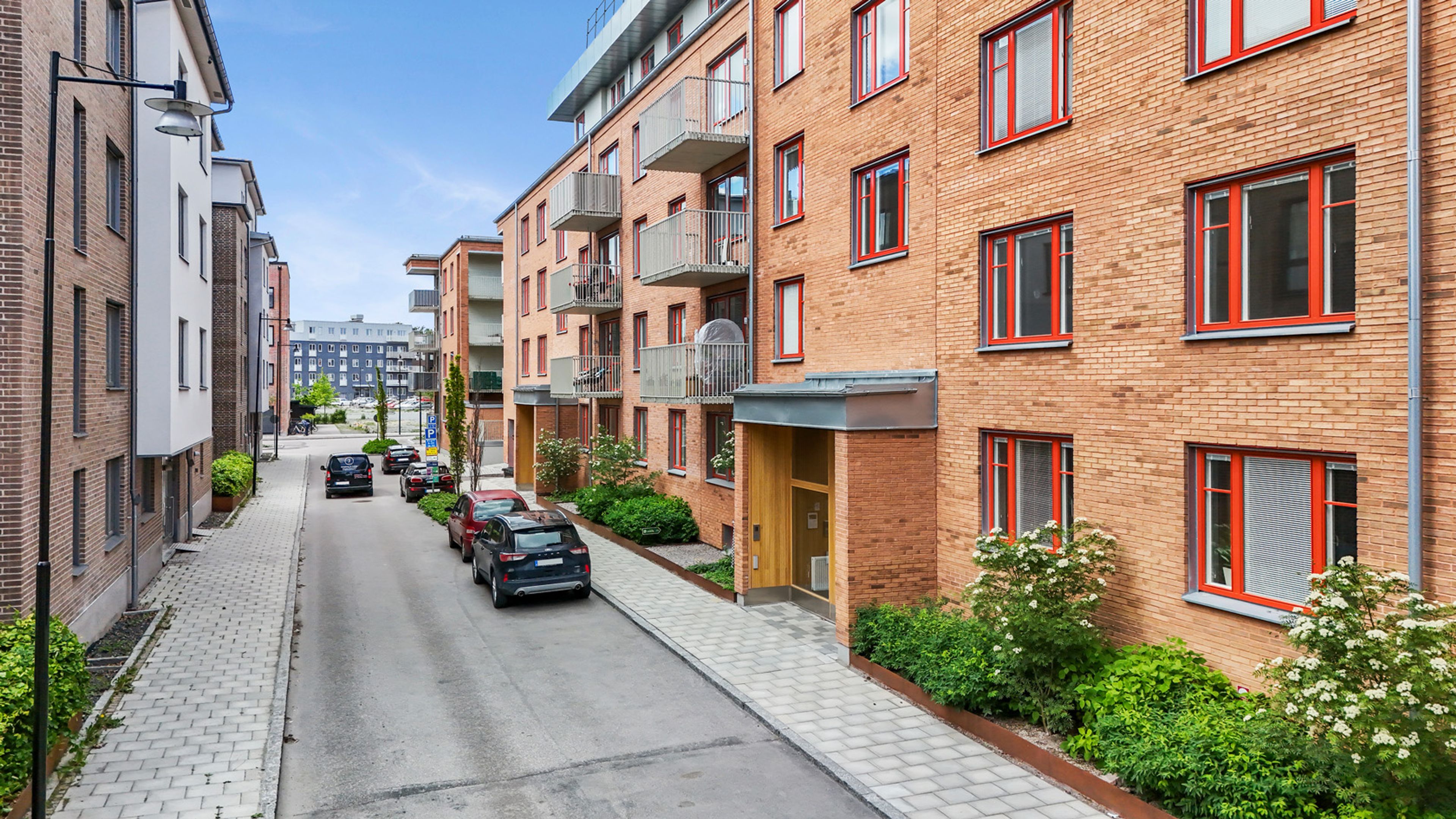 Foto på gatan och entrén till en teglat lägenhetshus