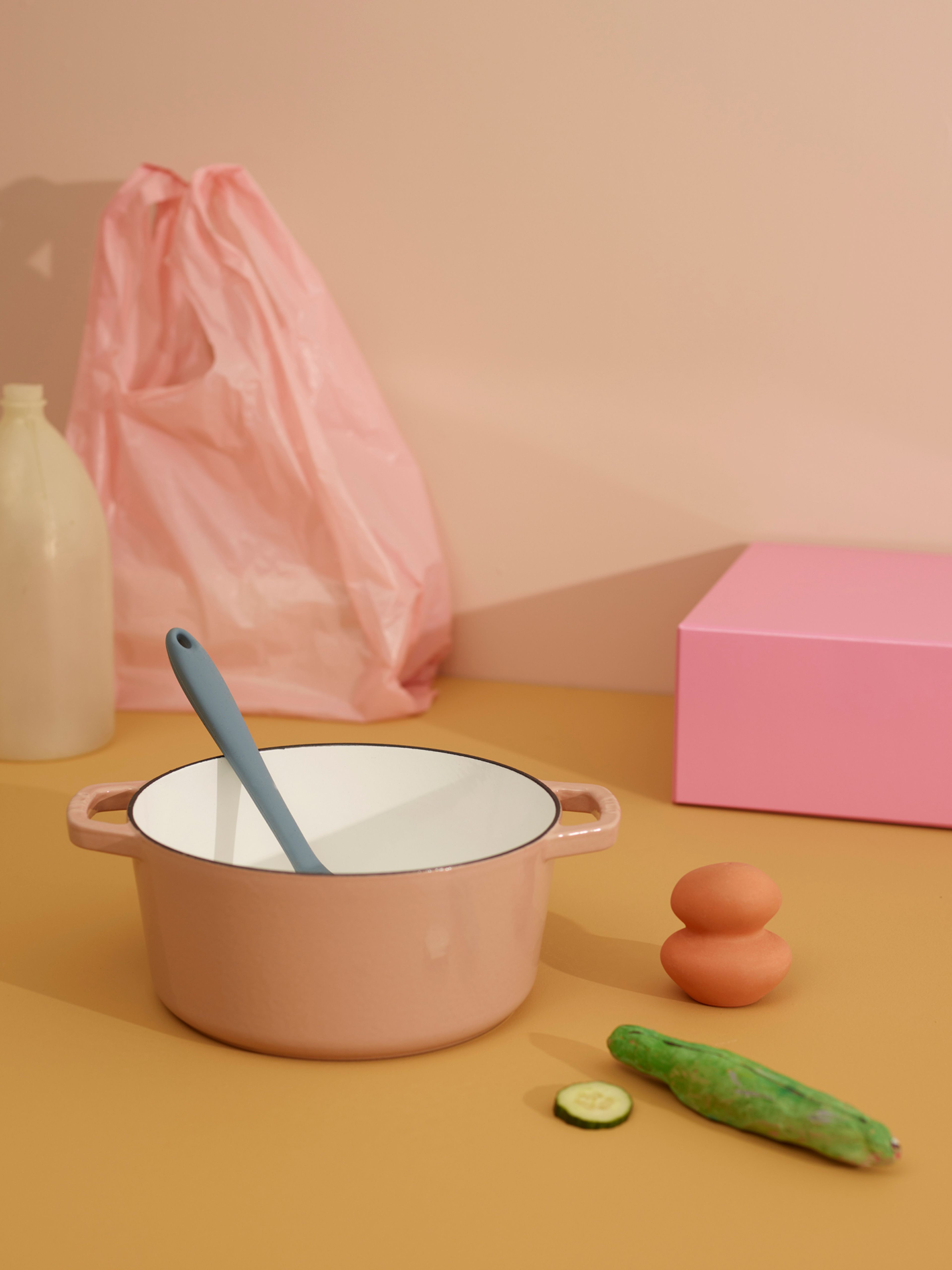Bilde av en rosa kasserolle med en sleiv i, en rosa pose, en agurk og noen egg, tatt i studio.