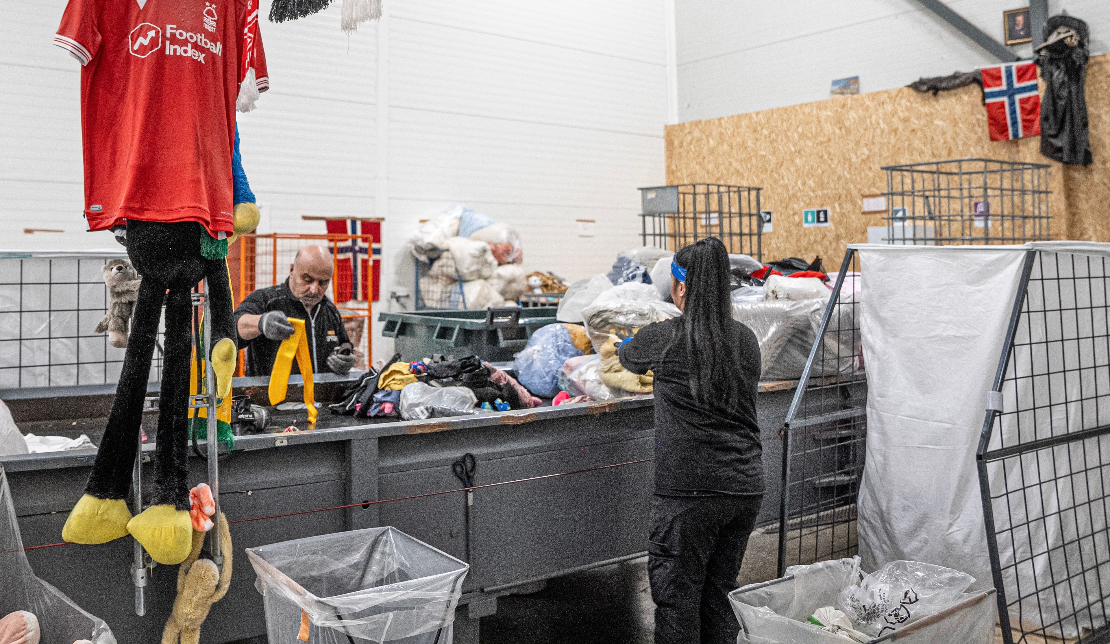 To personer sorterer brukte klær og tekstiler på et mottak hos Kirkens Bymisjon.