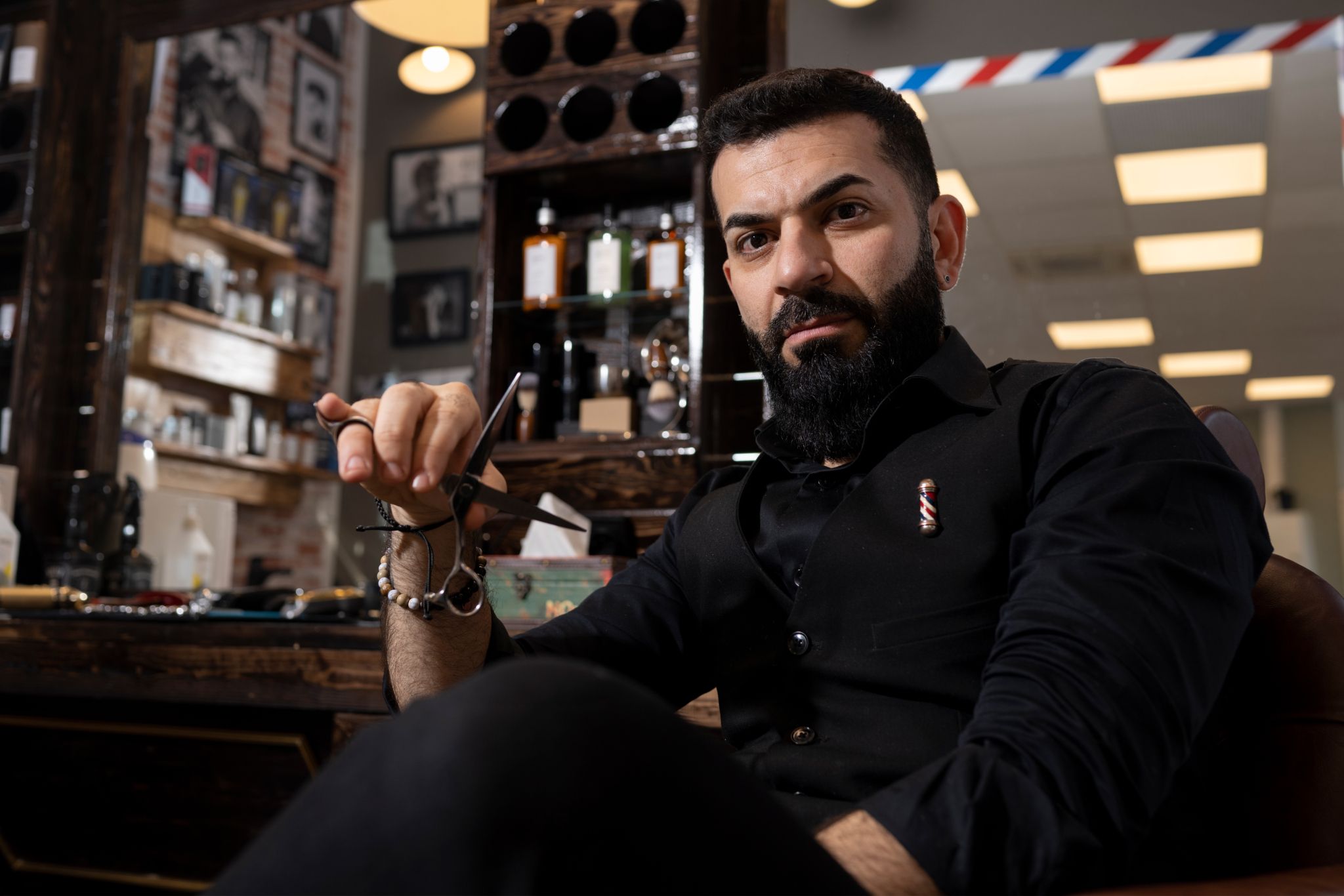 Karam sitter med en saks i sin egen frisørsalong på Holmlia.