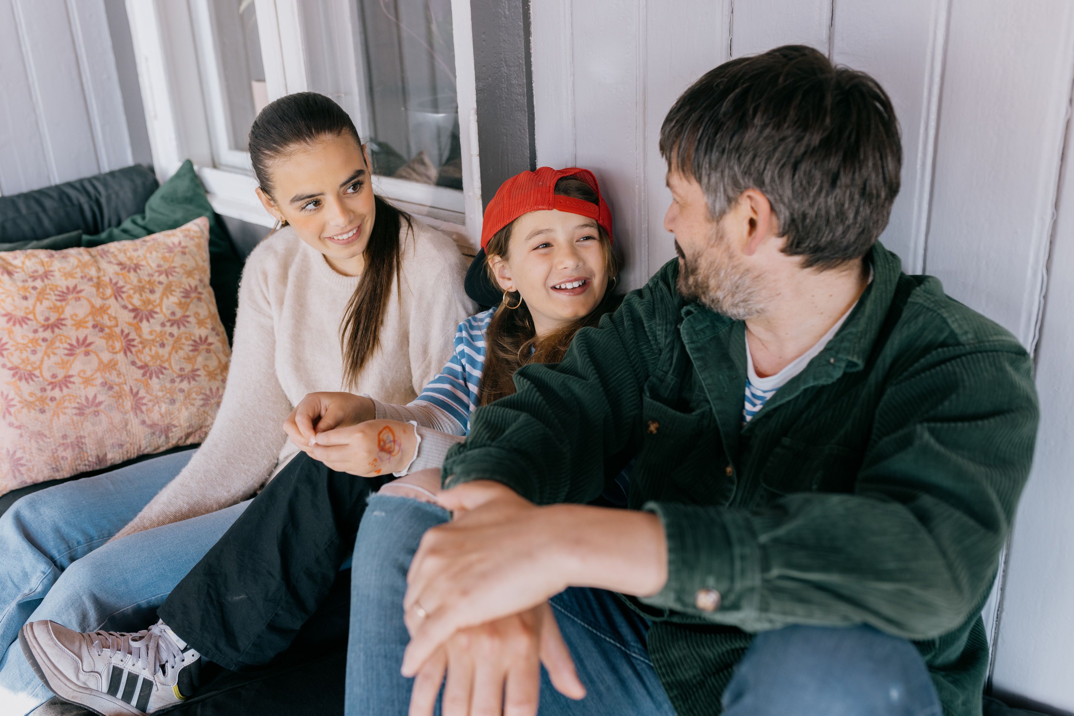 En familie sitter på verandaen og smiler.