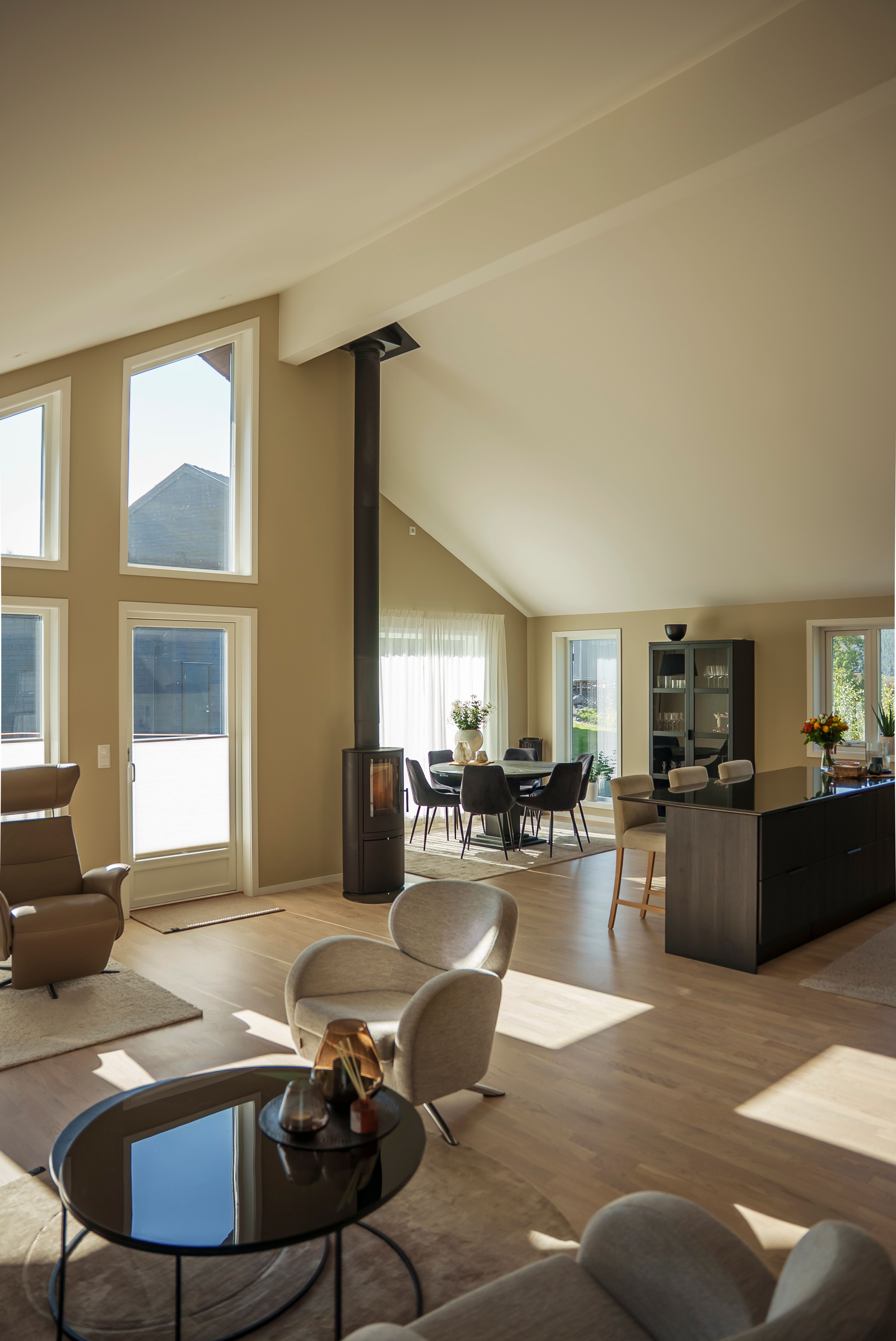 Oversiktsbilde av en lys, beige stue med peis og kjøkken