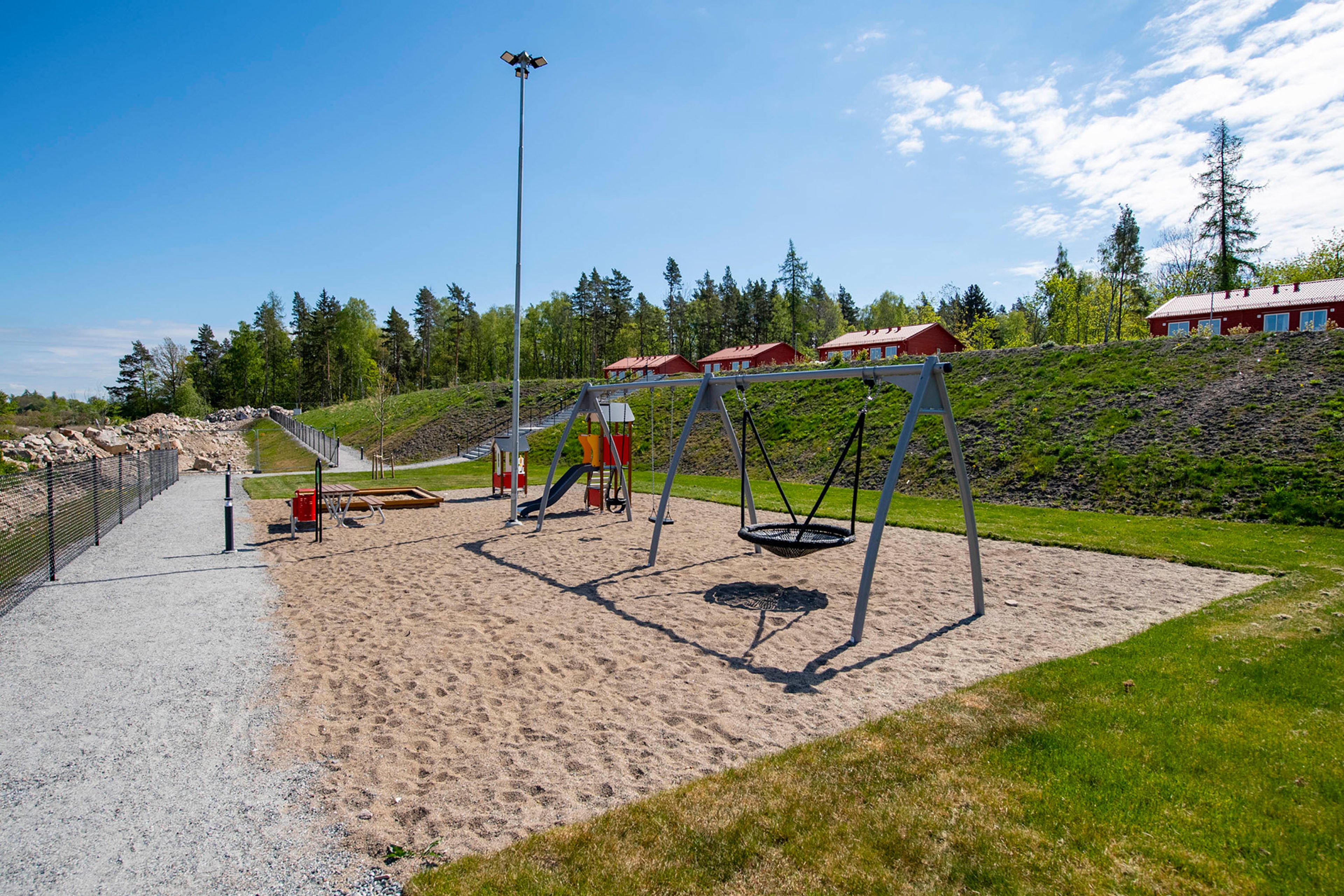 Lekplats med sandlåda, klätterställning och gunga i direkt anslutning till området