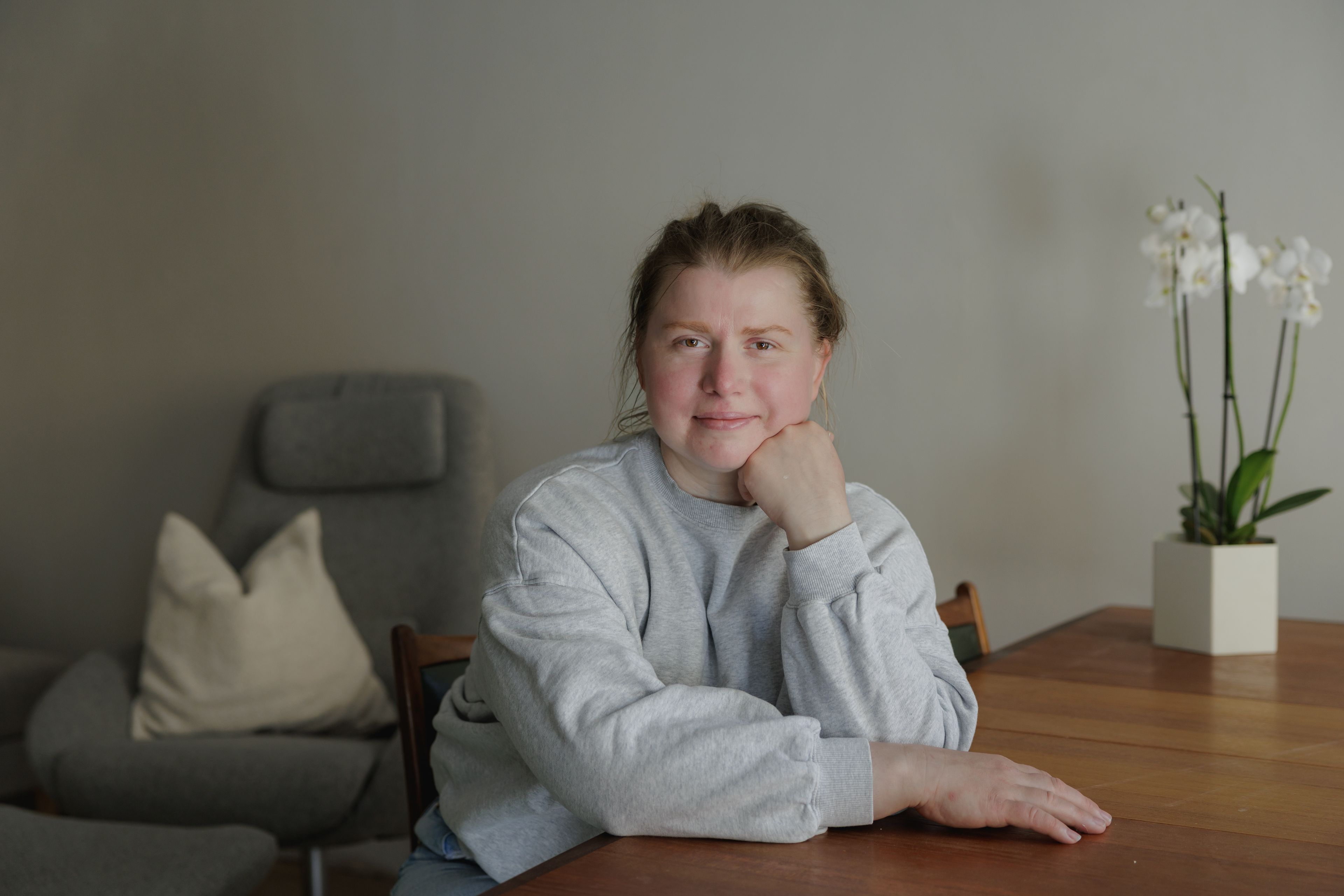 Viktora sitter ved et trebord inne og smiler mot kamera