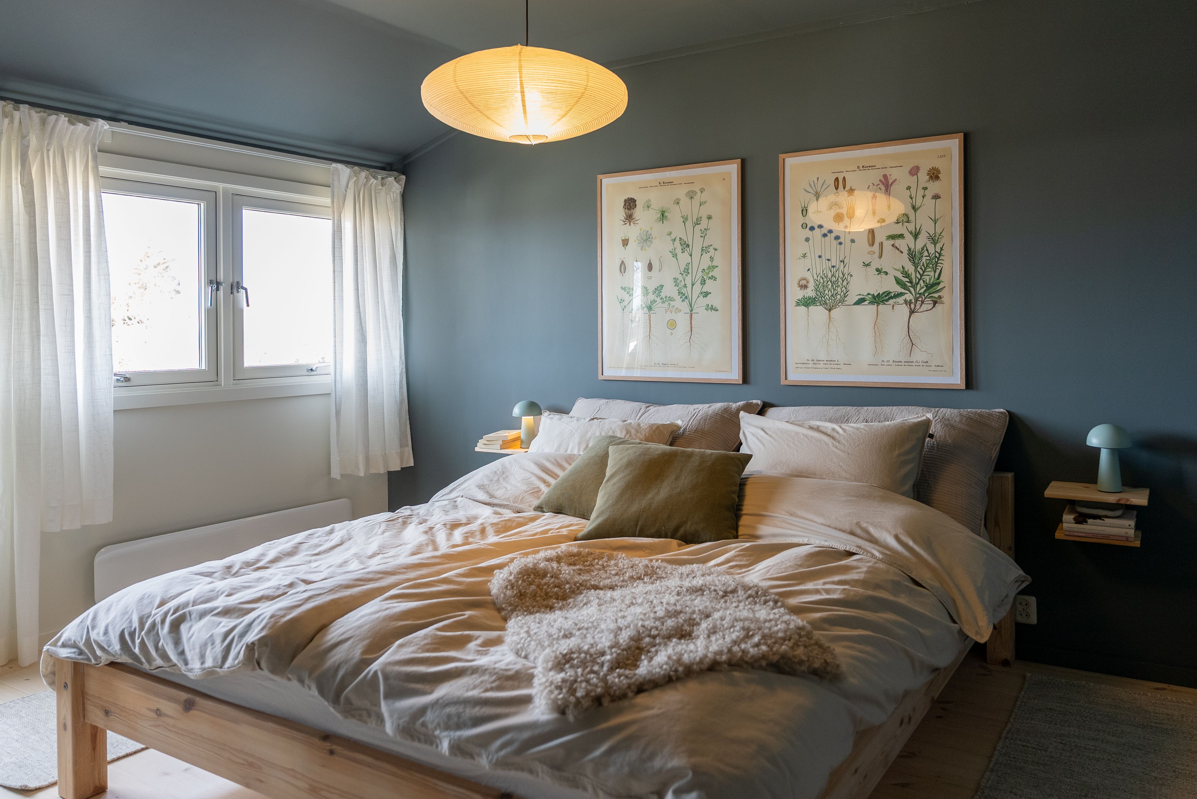 Et nyoppusset soverom med nymalte vegger, heltre furugulv og pent oppredd seng.