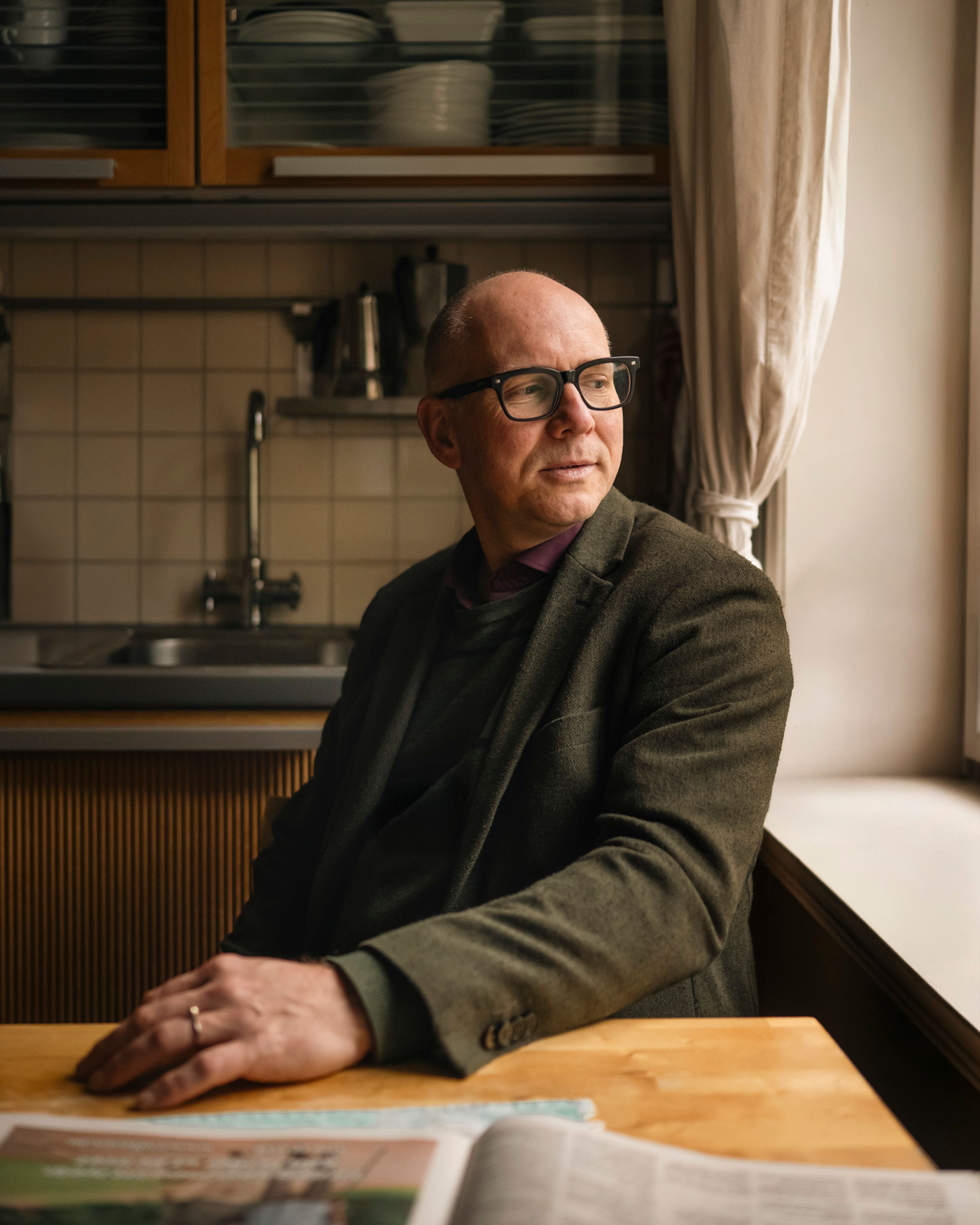 Styreleder Frank Martinsen sitter ved kjøkkenbordet i leiligheten sin og ser ut av vinduet.