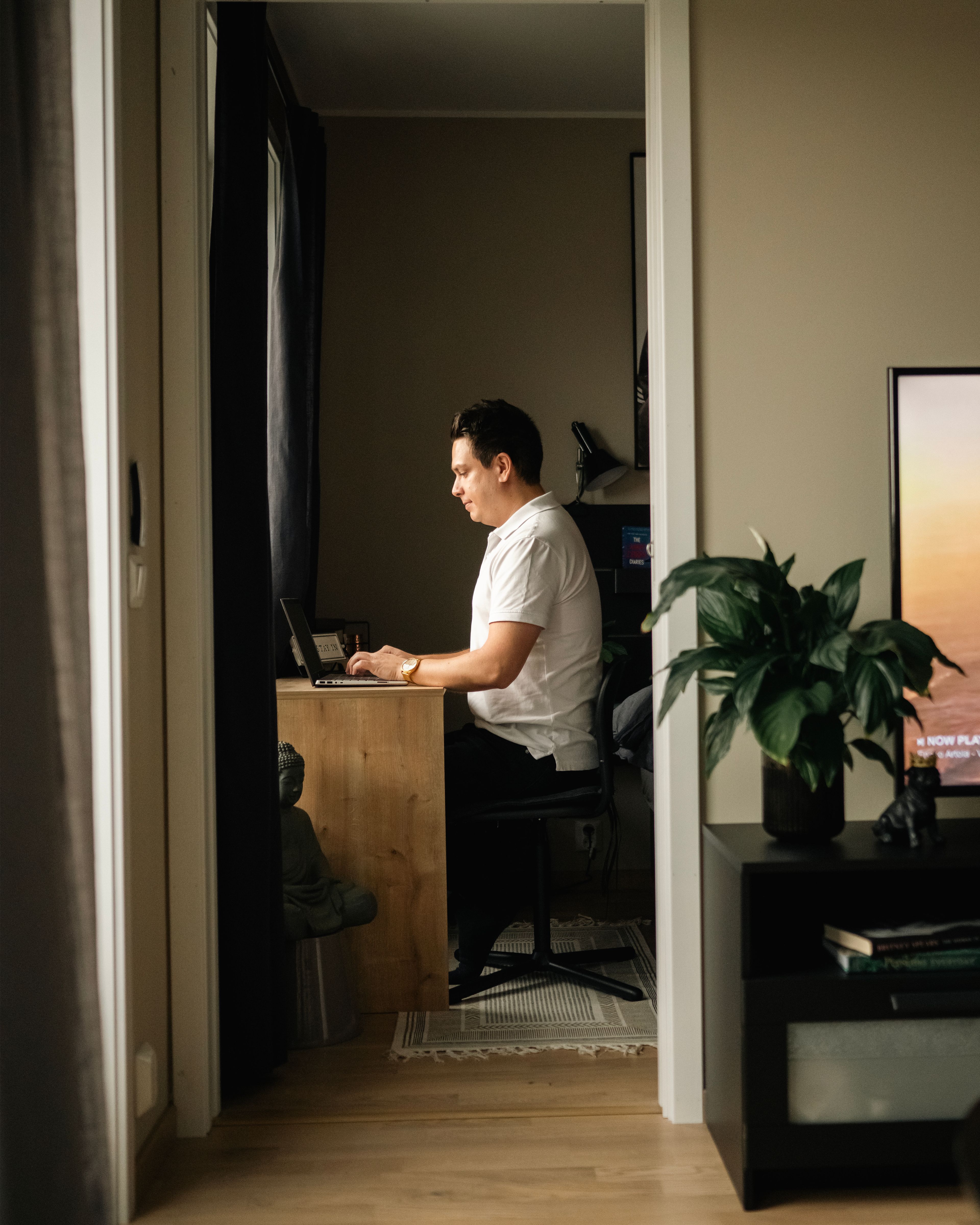 Foto av Andreas ved skrivebordet i leiligheten på Vollebekk