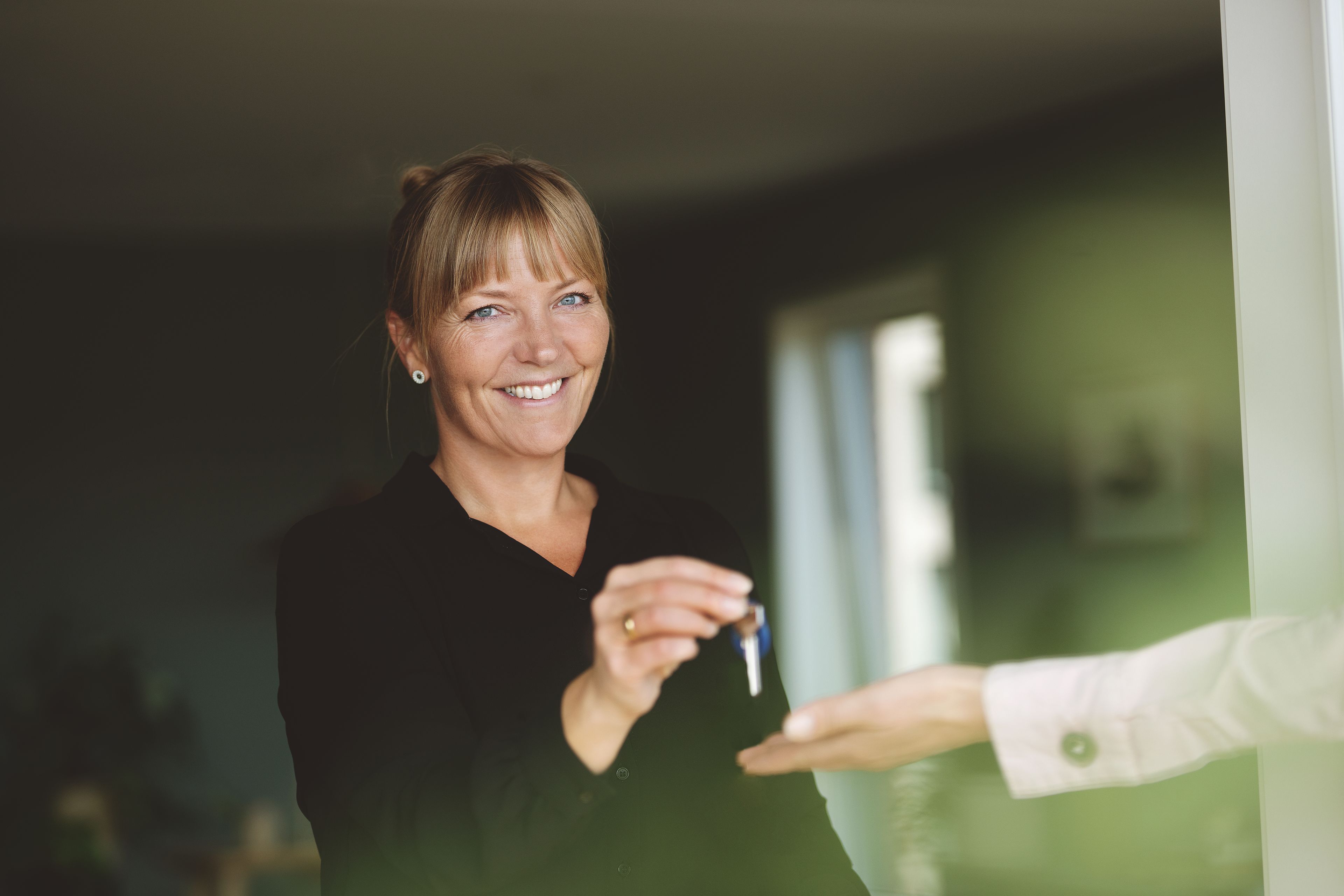 En eiendomsmegler som gir nøkler til en ny boligeier.