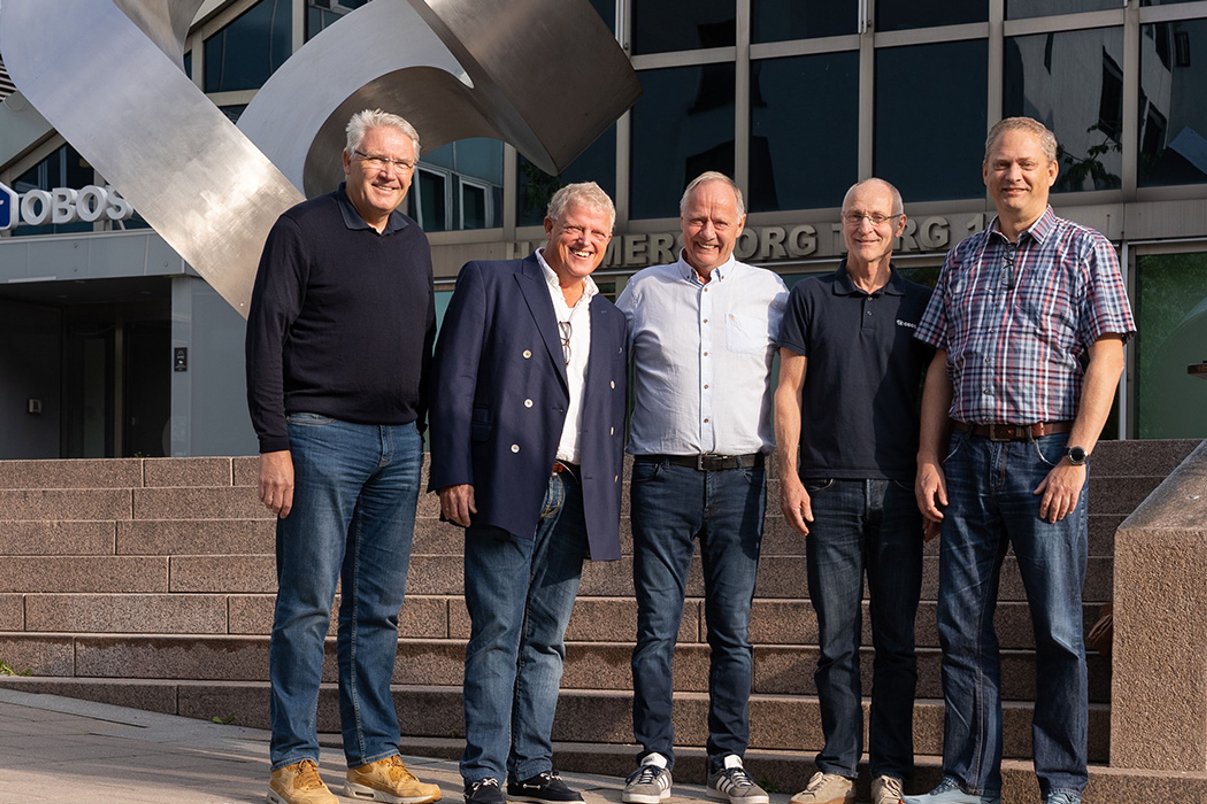 Fem menn fra driftsavdelingen hos OBOS Eiendom står foran statuen på Hammersborg Torg.