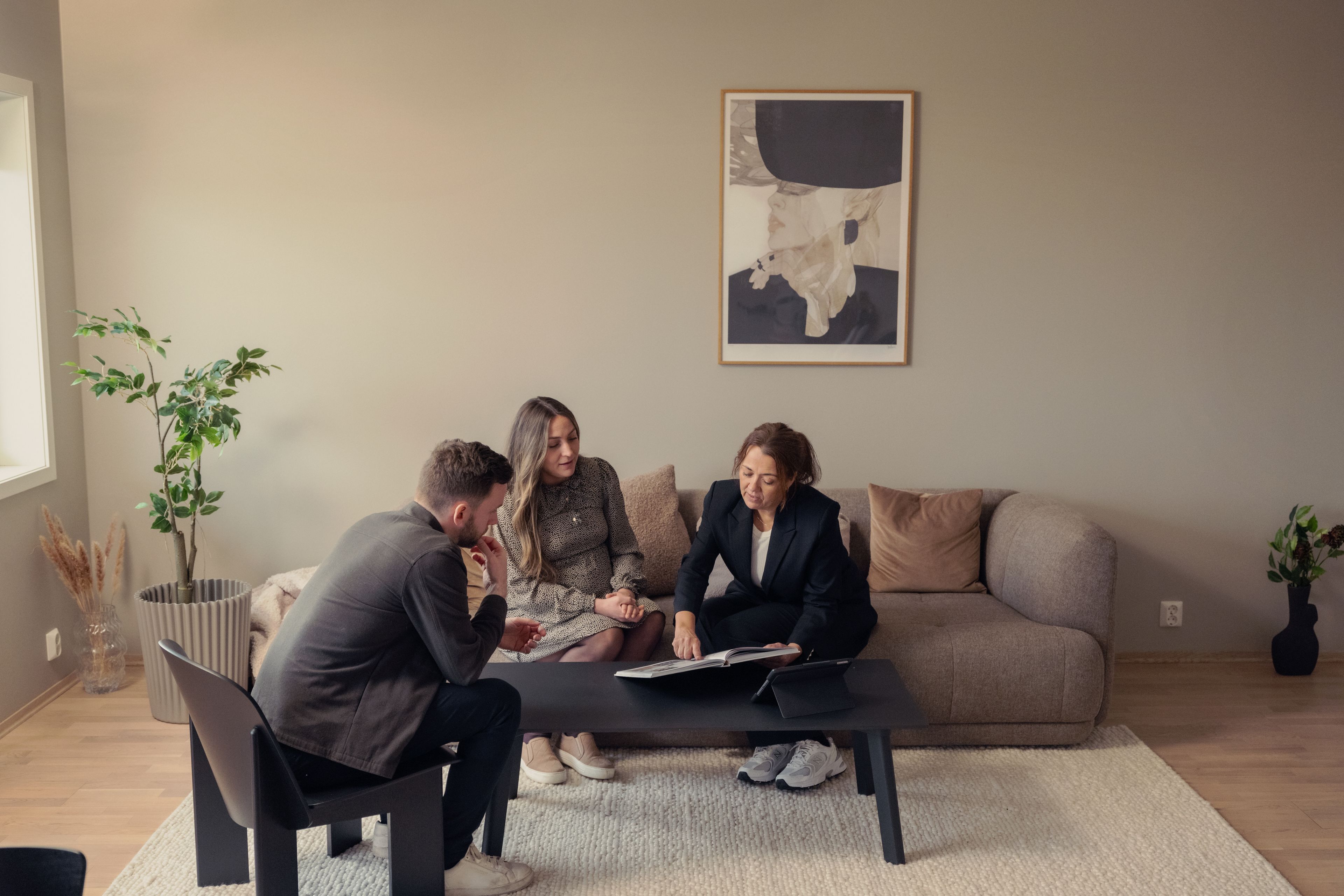 Tre mennesker sitter i en sofa og ser på et prospekt.