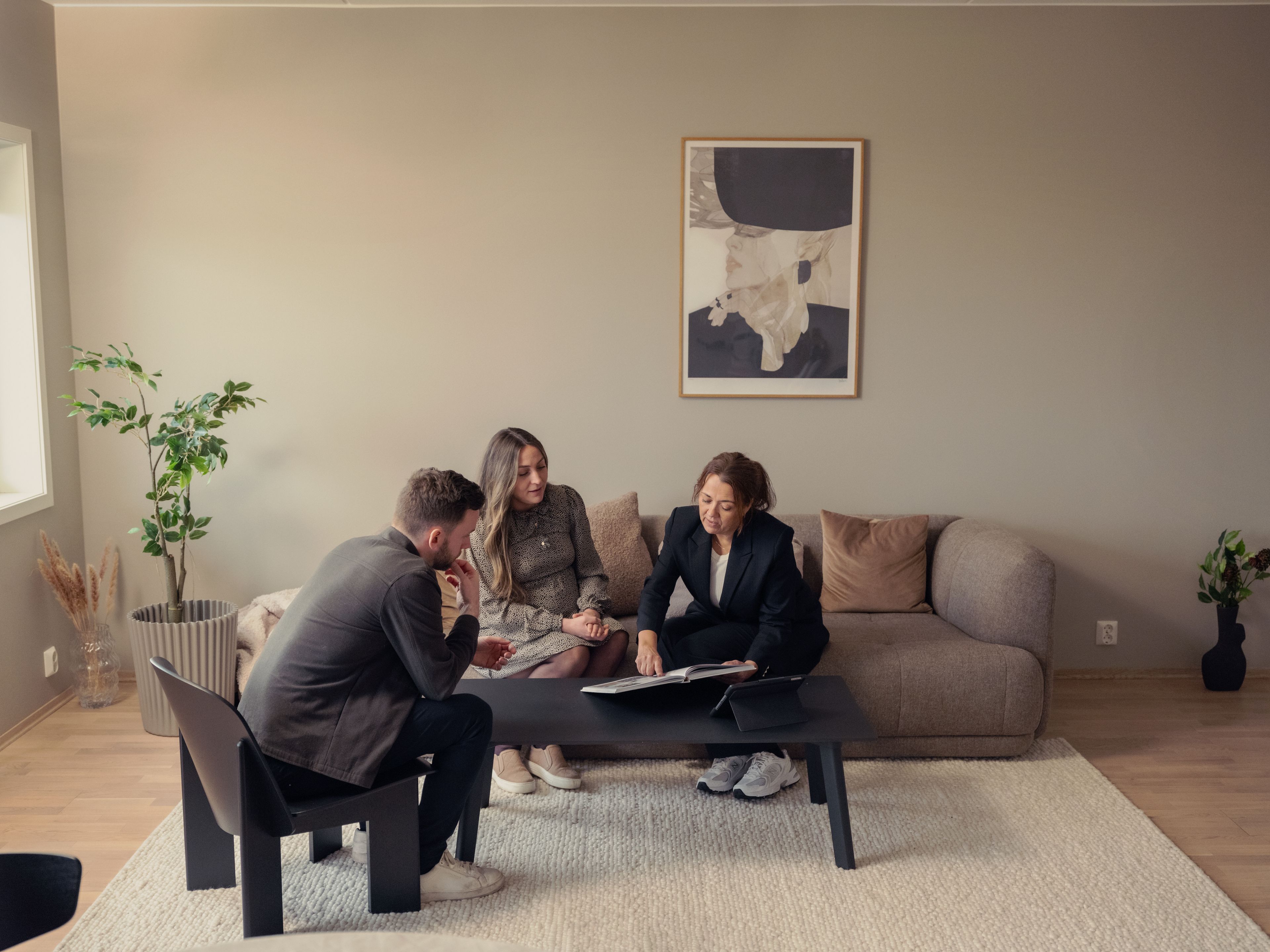 Megler som sitter sammen med en mann og en dame som vil kjøpe bolig.