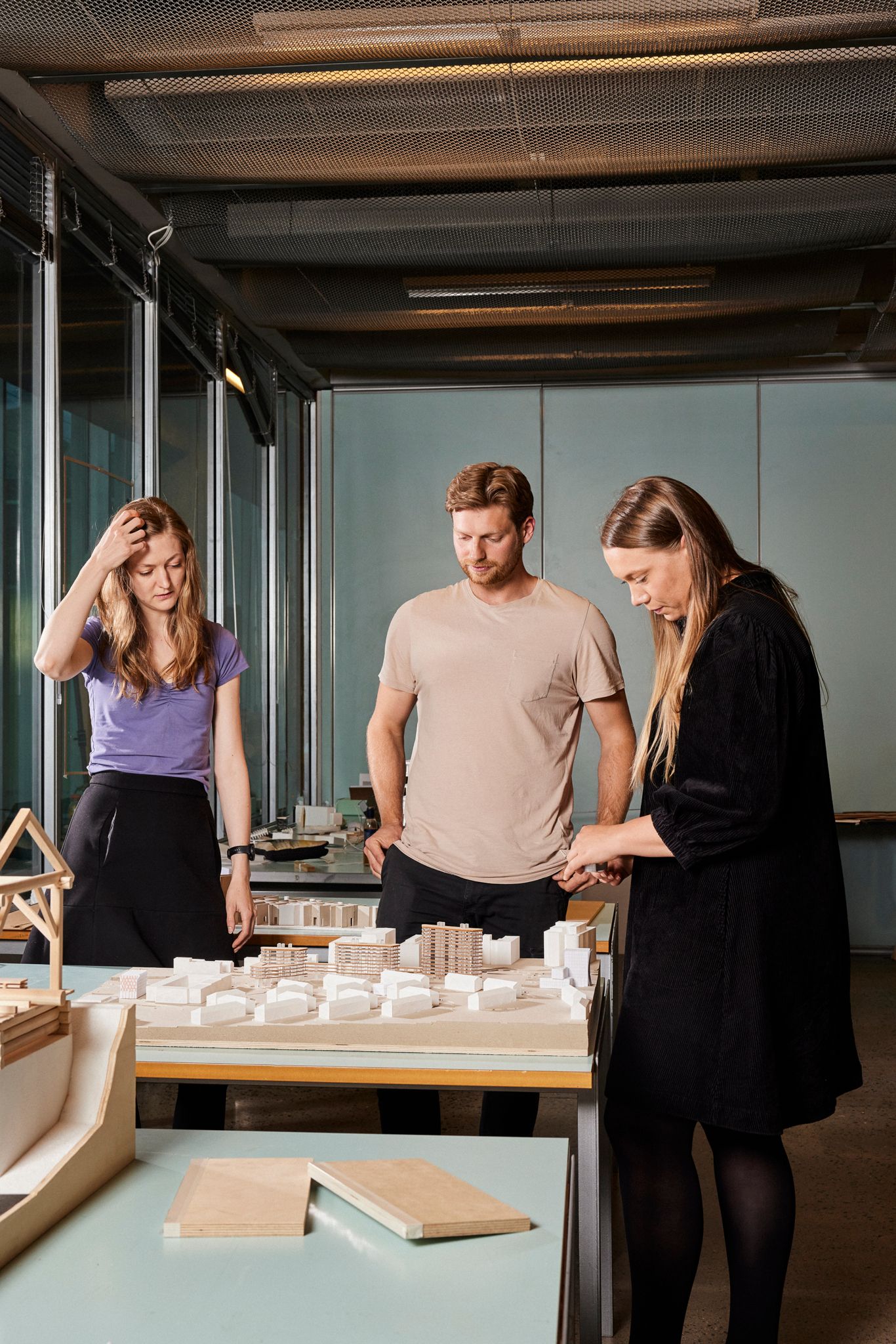 Silje, Jonas og Siren står foran en modell med flere bygninger.