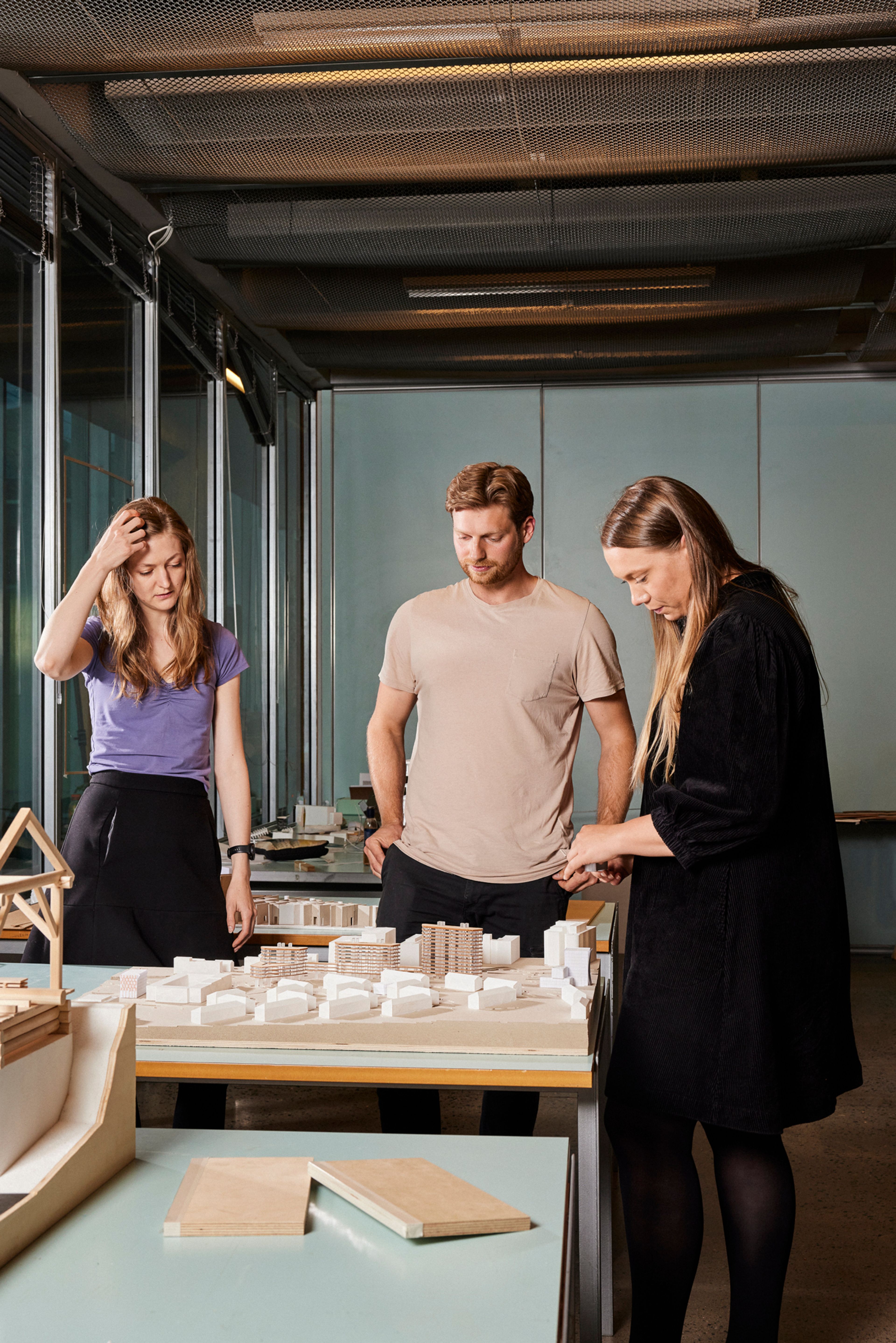 Silje, Jonas og Siren står foran en modell med flere bygninger.