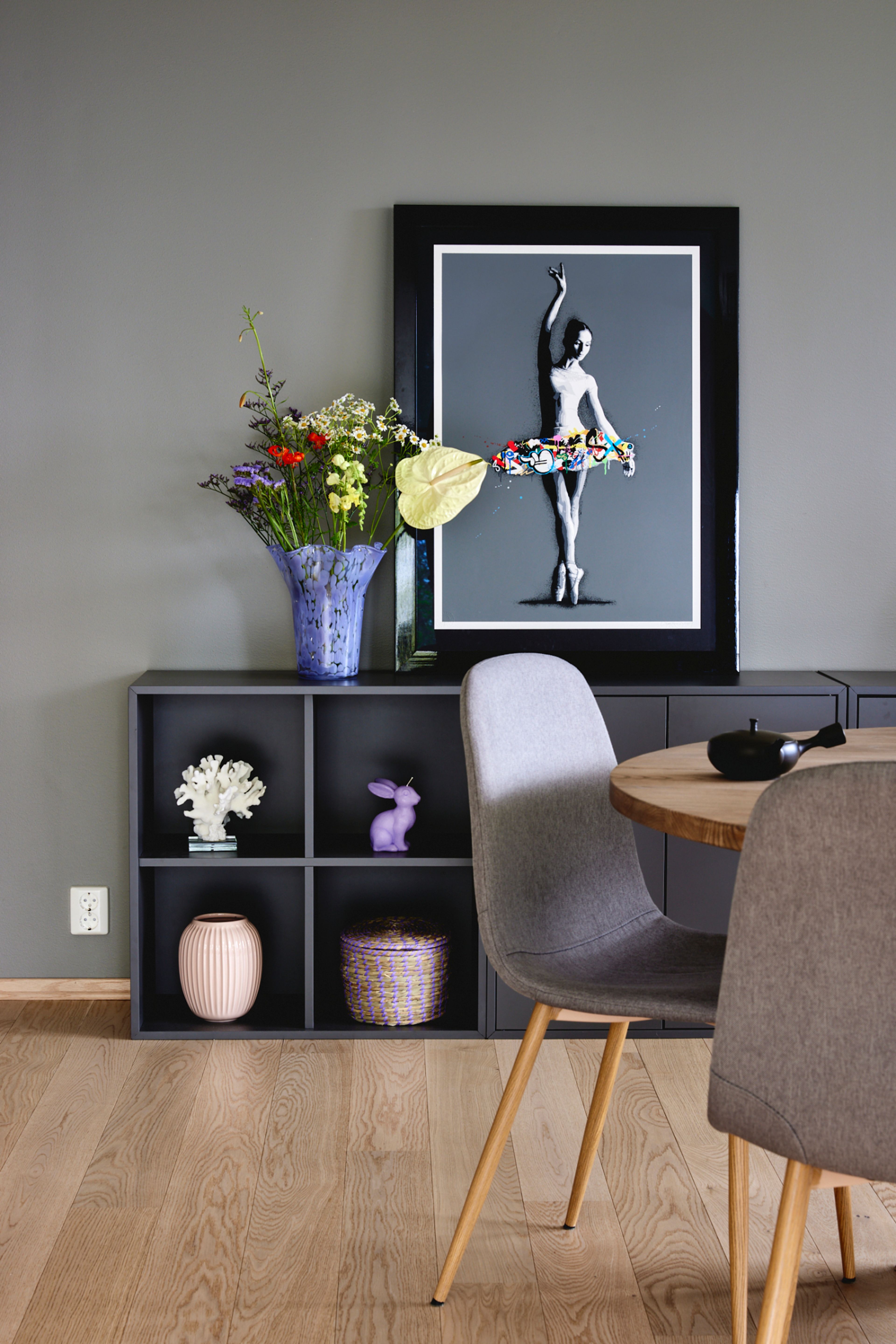 Spisebord og spisestuestoler i forgrunnen, skjenk med hyller i bakgrunnen.