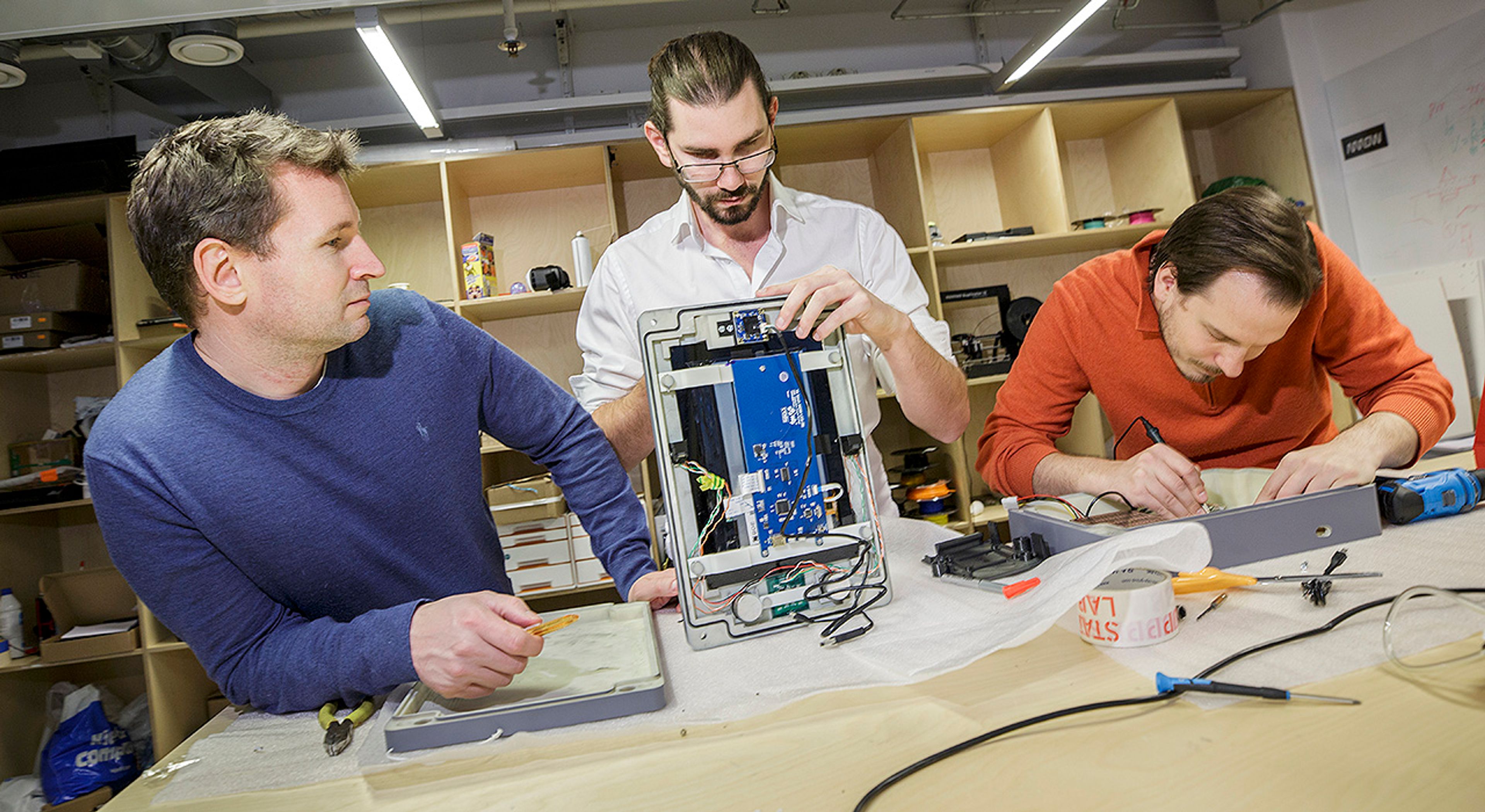 Tre personer jobber med en teknologisk duppedings.