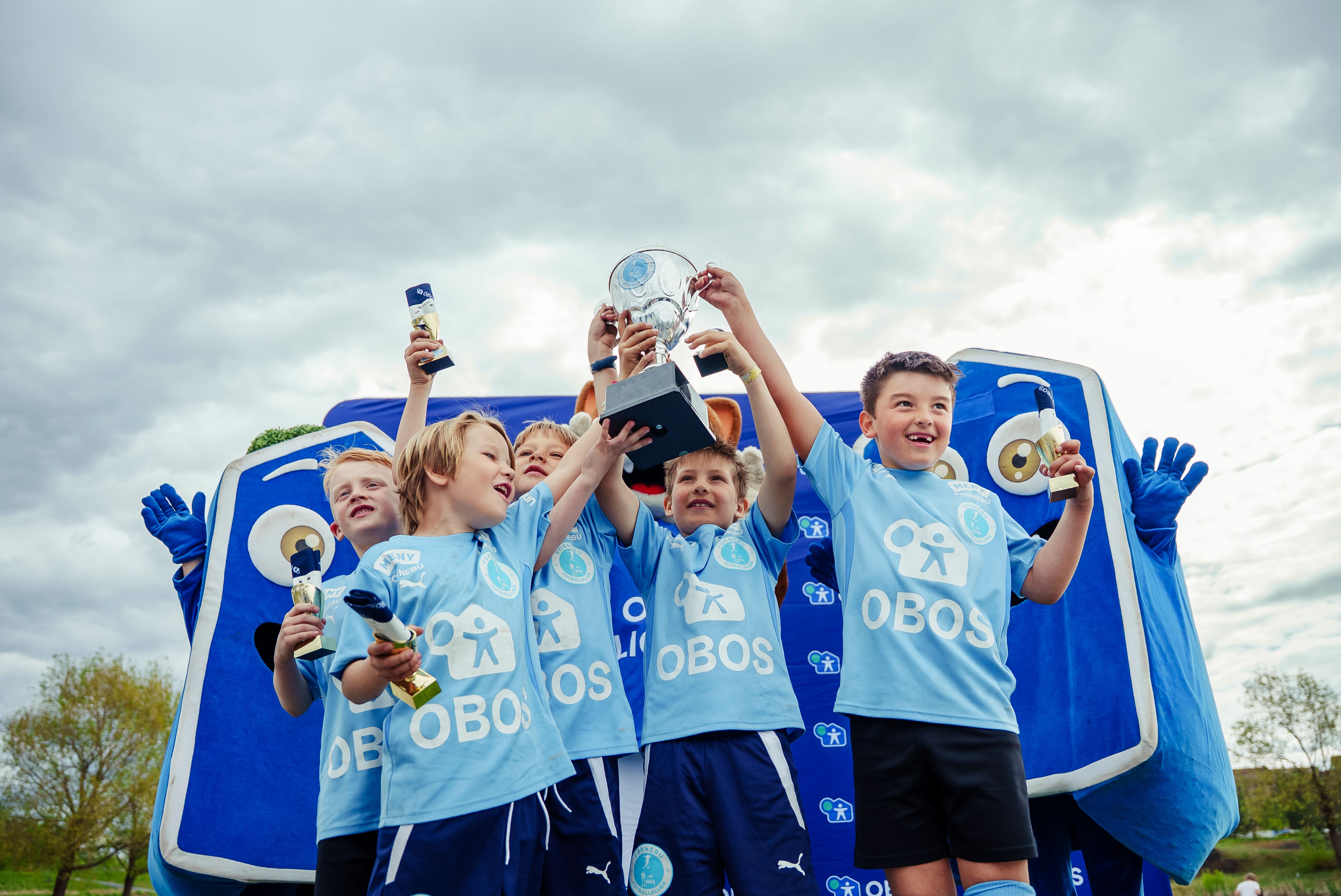 Barna som har deltatt på OBOS Miniliga feirer at de har fått pokal.