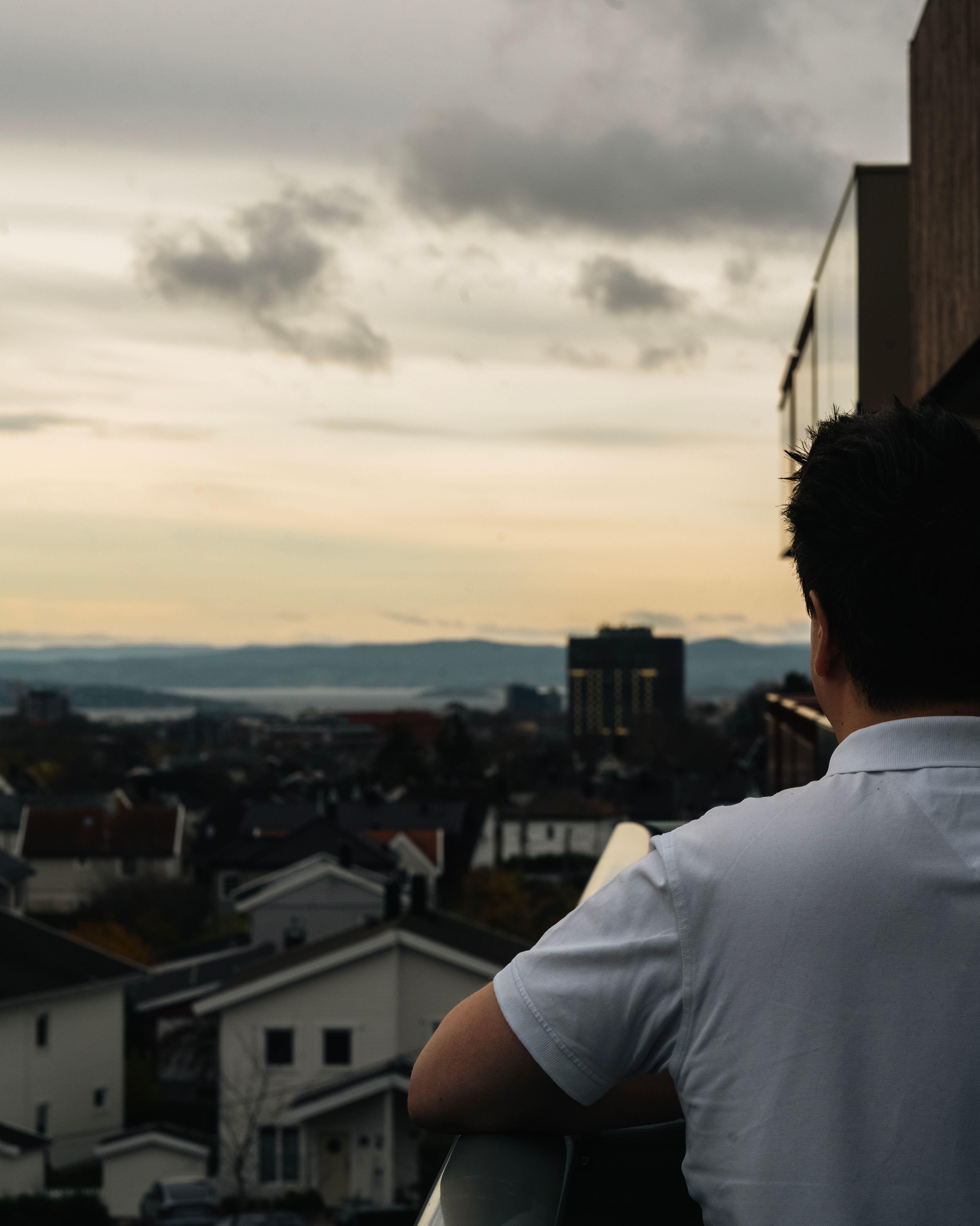 Foto av Andreas som ser ut over Oslo fra balkongen i leiligheten sin på Vollebekk