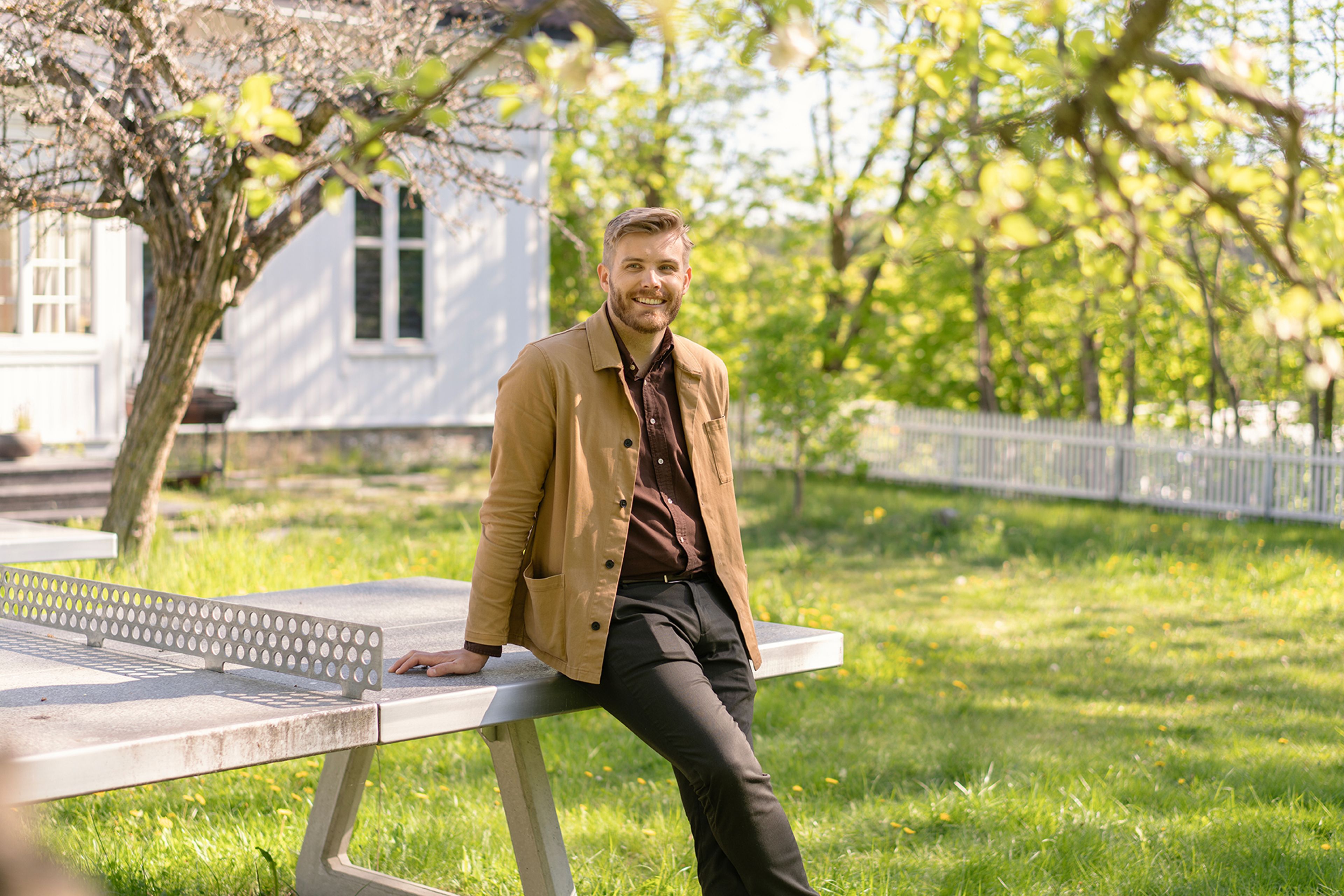 Foto av Kent Olav Nordby som sitter på et bordtennisbord på sommeren.