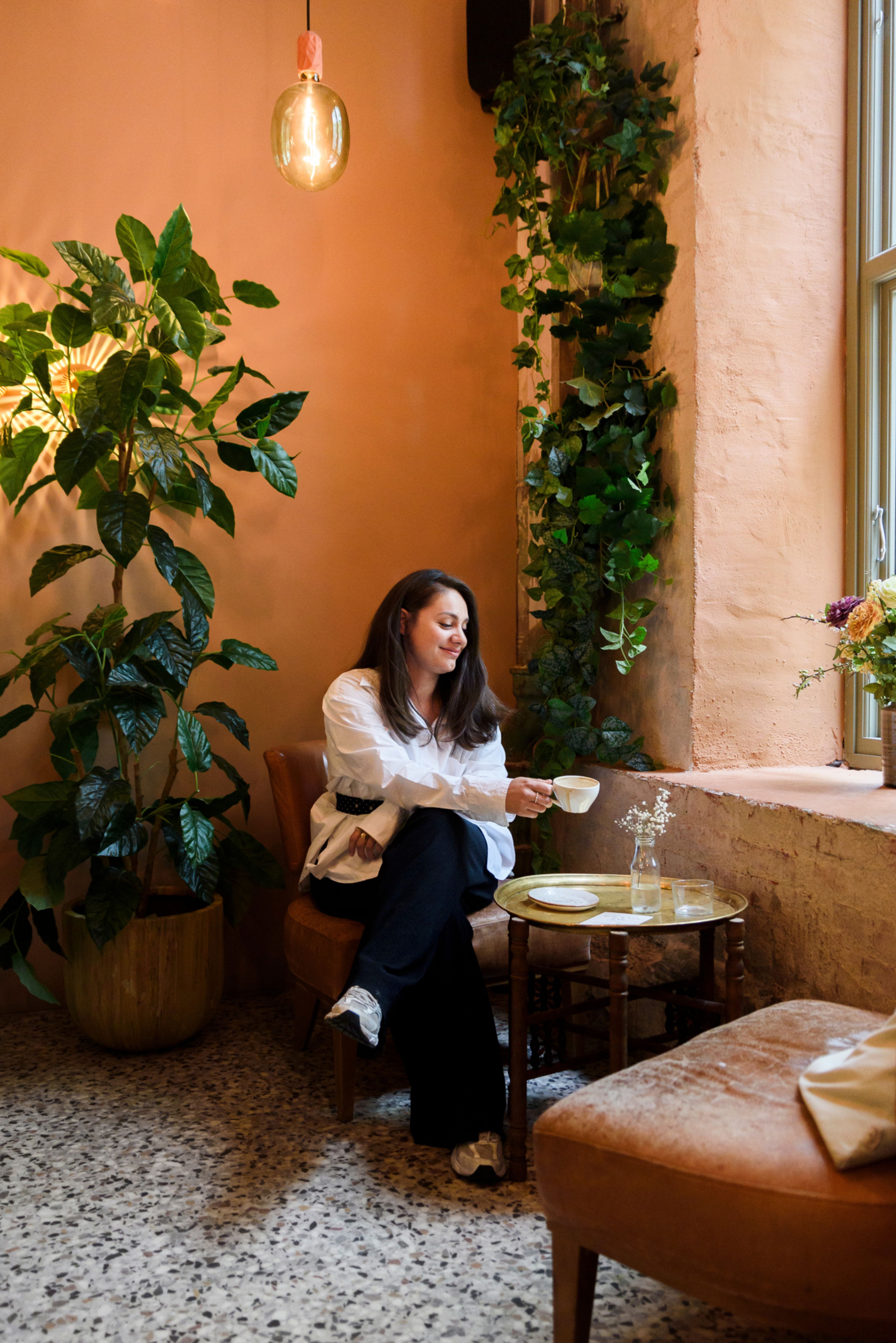 Jenny Andersen sitter foran en oransje vegg i kafeen Håndbakt
