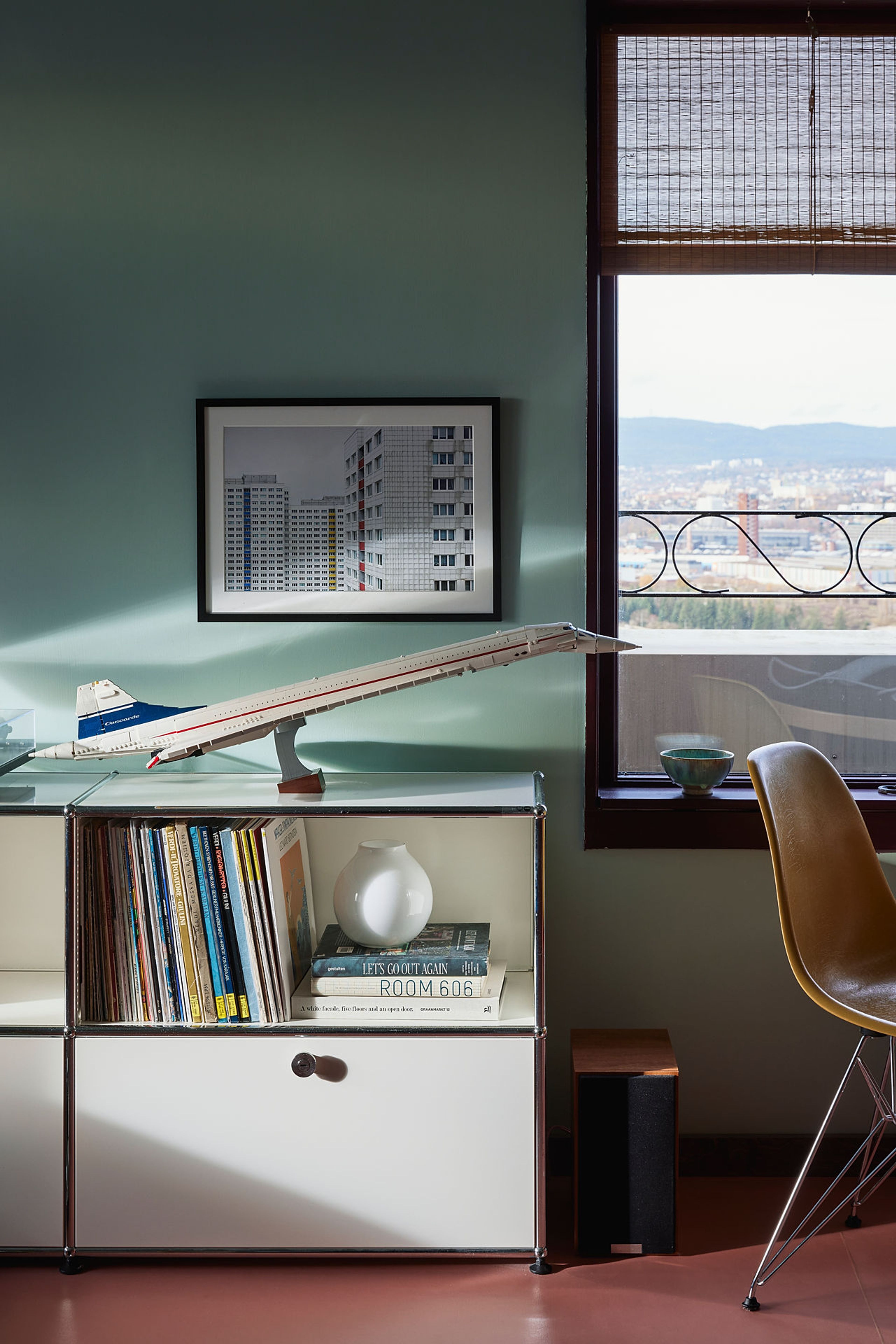 Bildet av en bokhylle som står siden av et vindu med utsikt over byen.