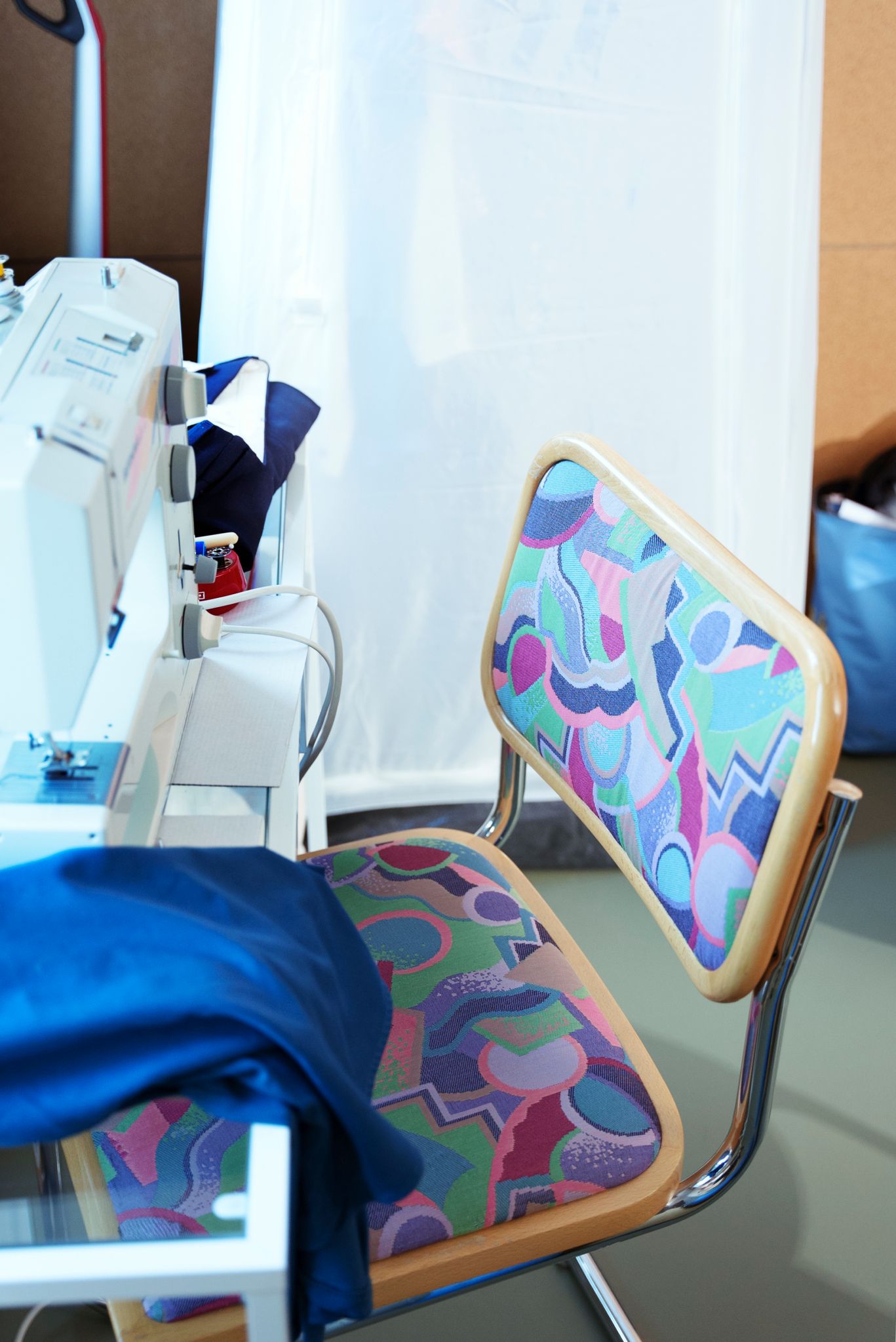 Detaljbilde av en stol i retro stoff foran et bord med en symaskin på