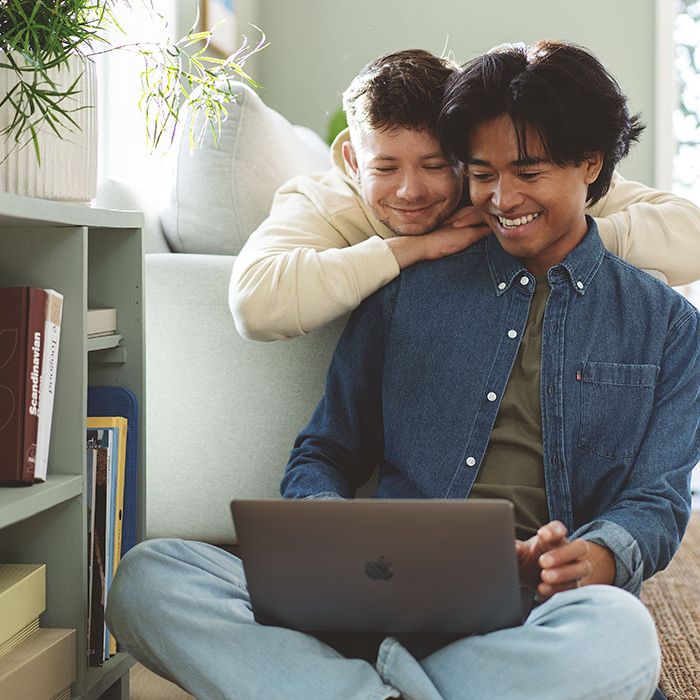 Ungt par ser på laptopskjerm og smiler