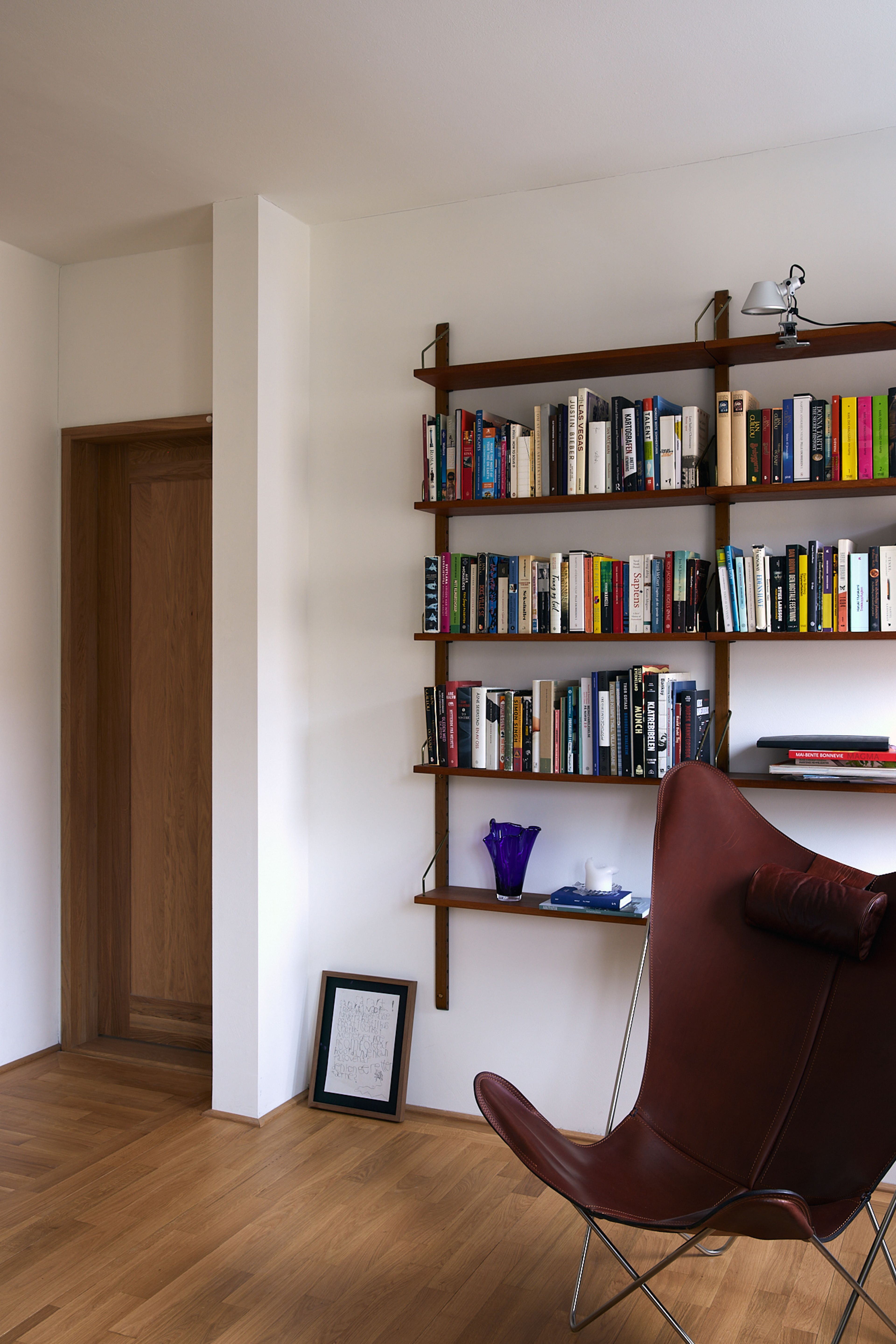 Bilde av bibliotekskroken med bøker i hylla og en skinnstol fremfor hylla.