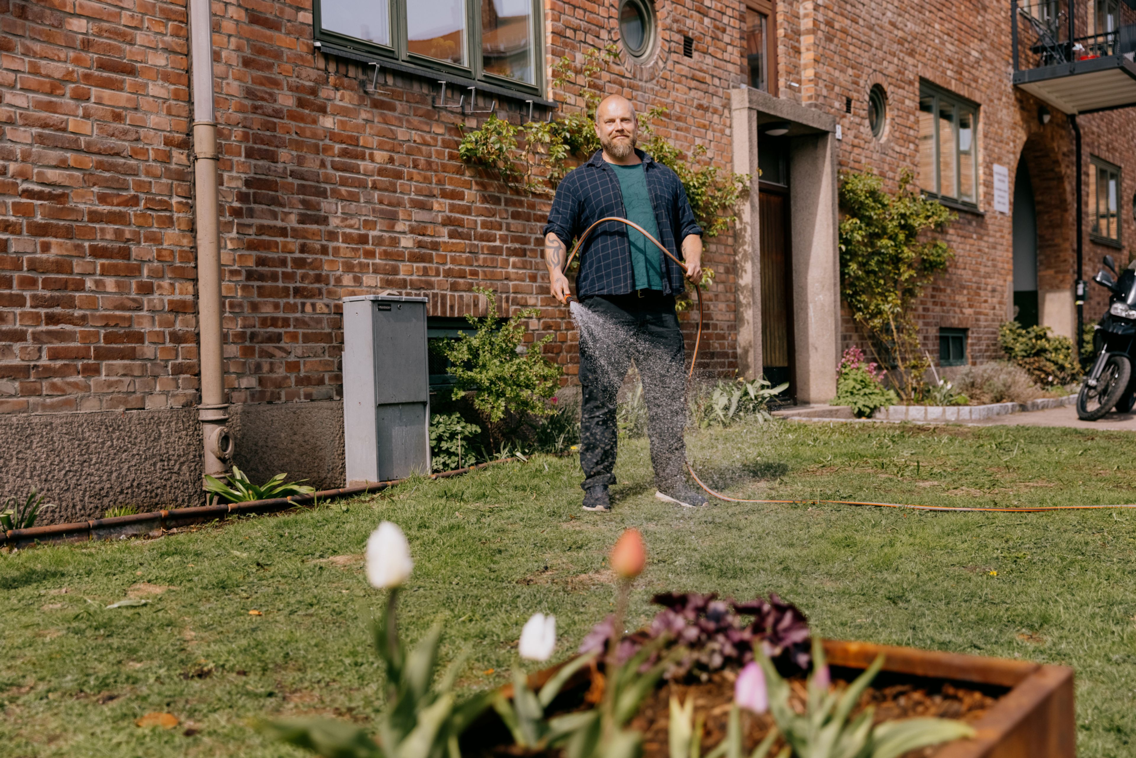 Foto av Thomas Vandraas som vanner plenen utenfor blokka