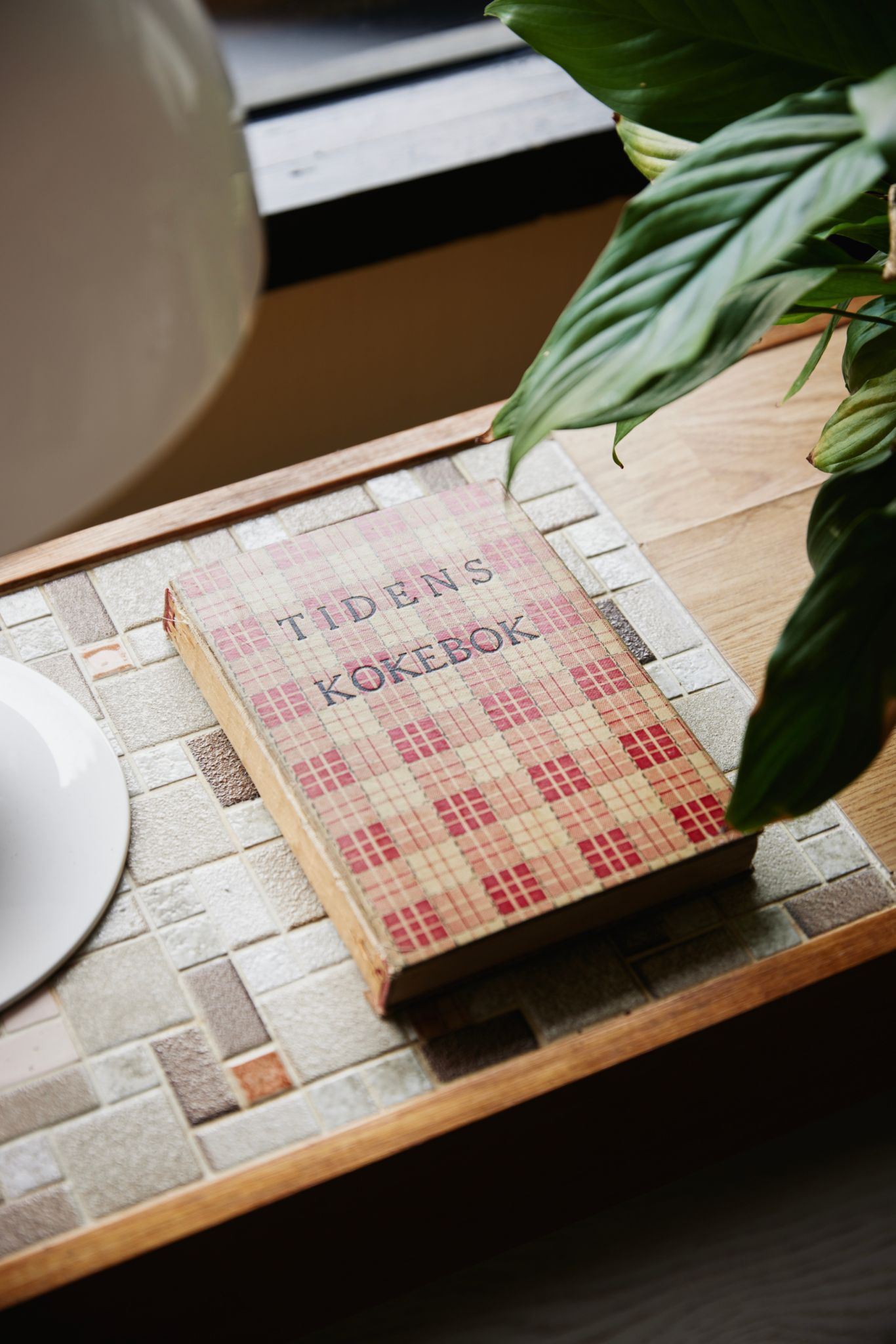 En kokebok ligger på en sittebenk med fliser.