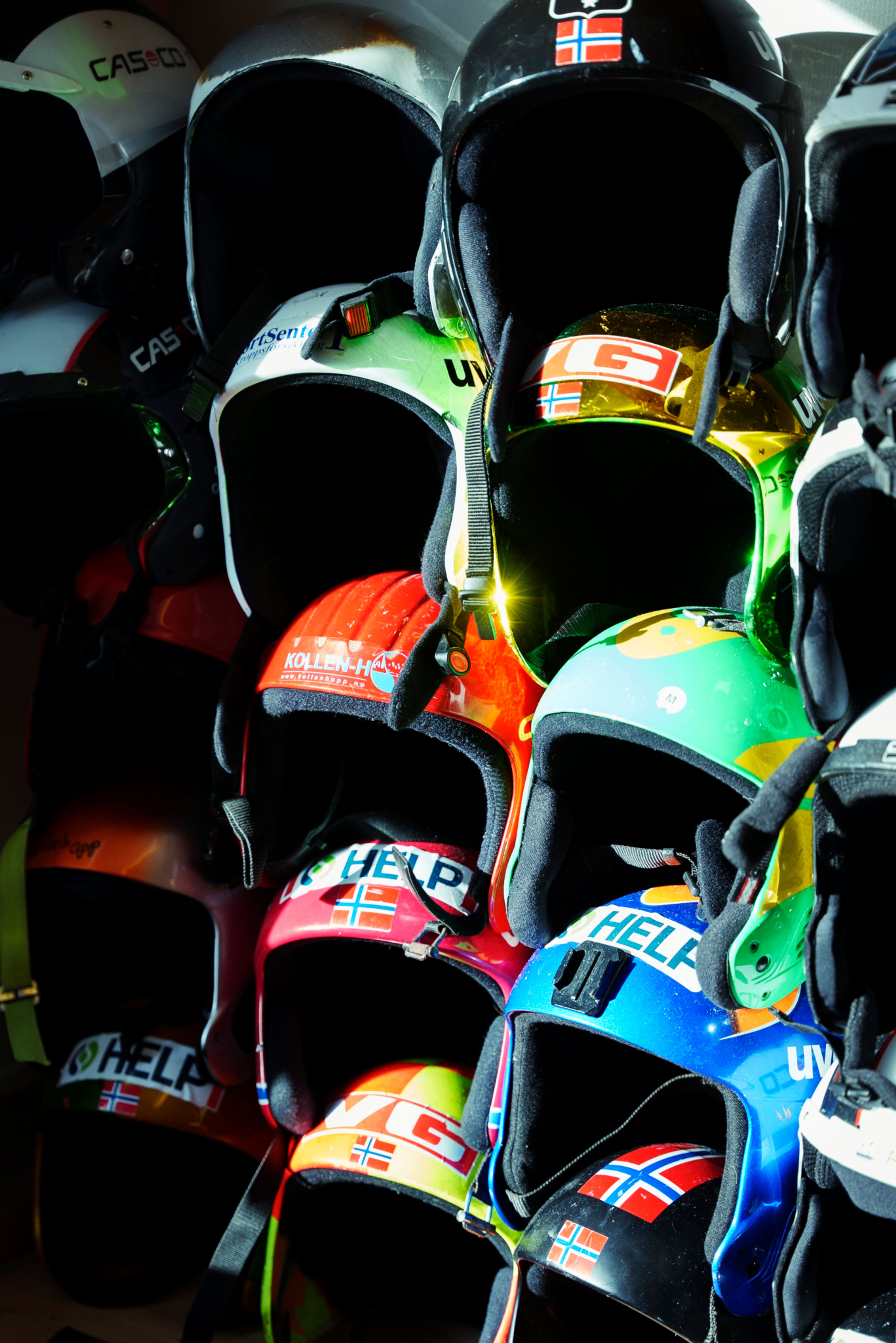 Skihjelmer som henger på en vegg med solen skinnende på dem.