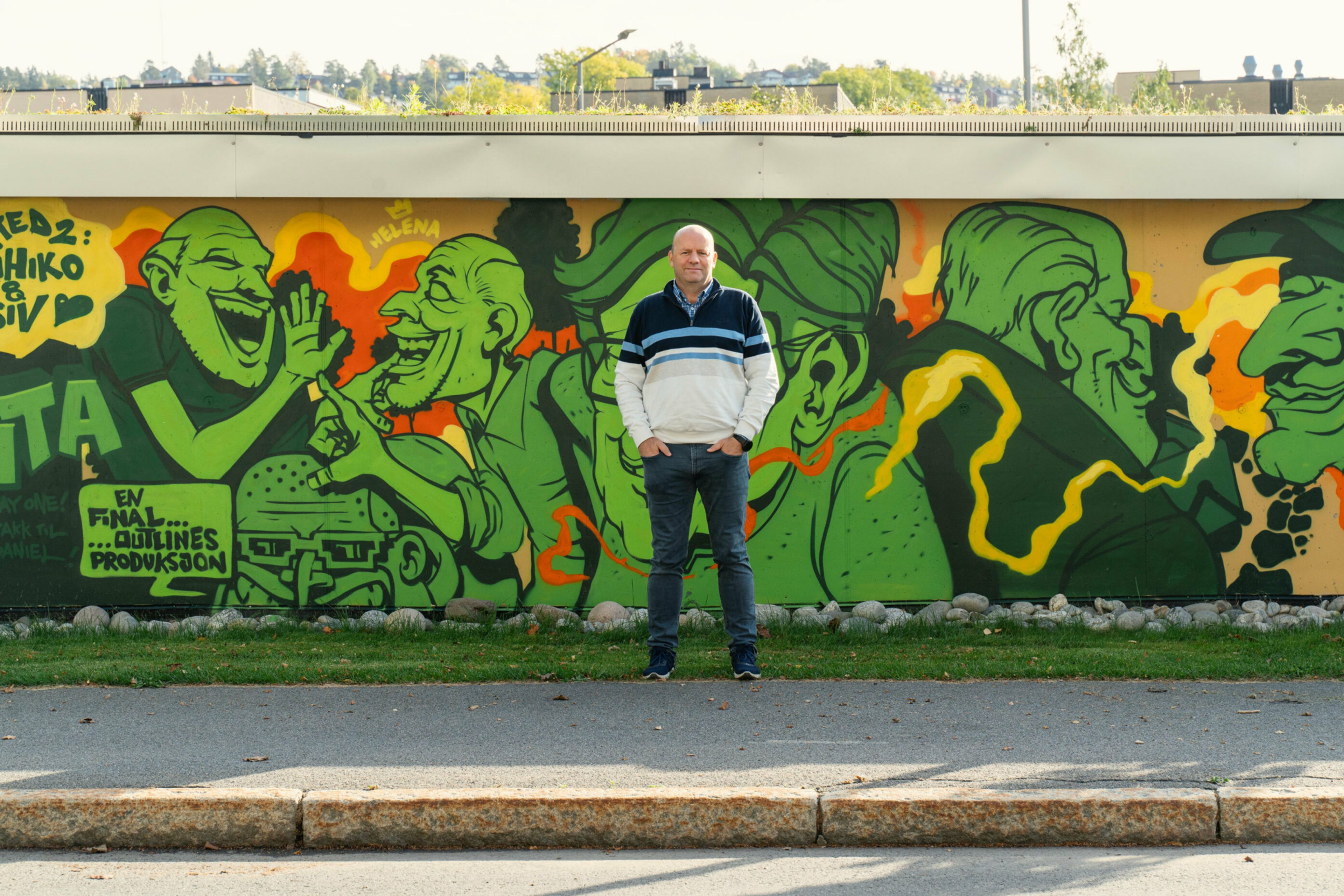 Ole Morten Øversjøen, daglig leder i Tveita borettslag, står foran grafittiveggen som viser flere av de som bor i borettslaget.