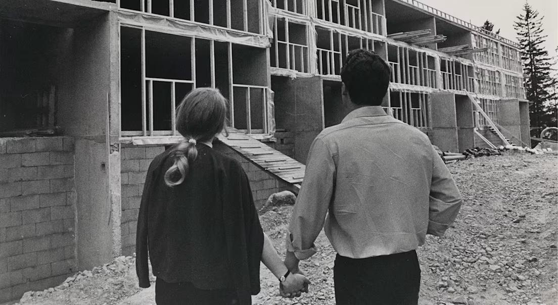 Et par som holder hender på en byggeplass Sandbakken.