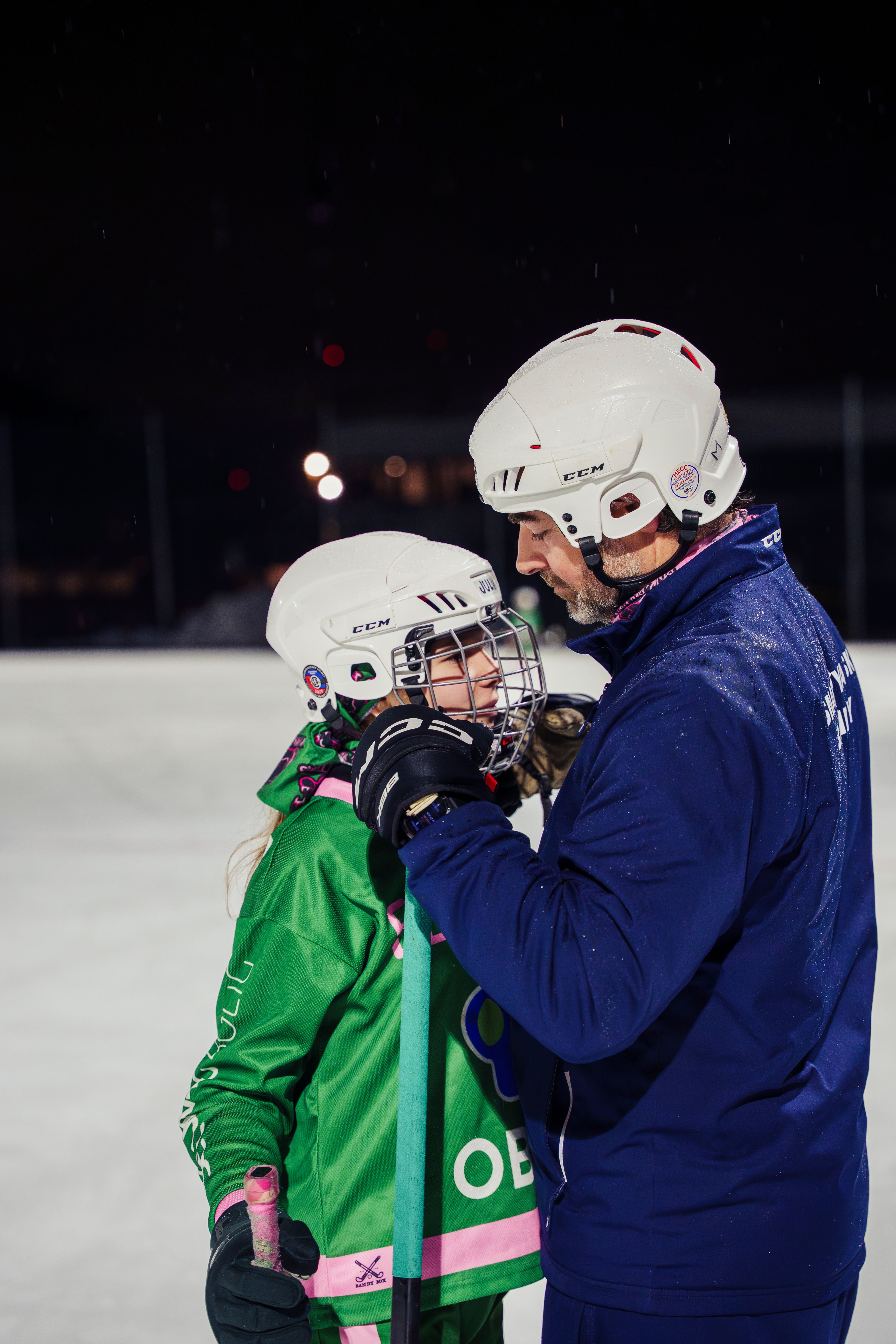 En av spilleren får hjelp til å feste hjelmen av treneren.