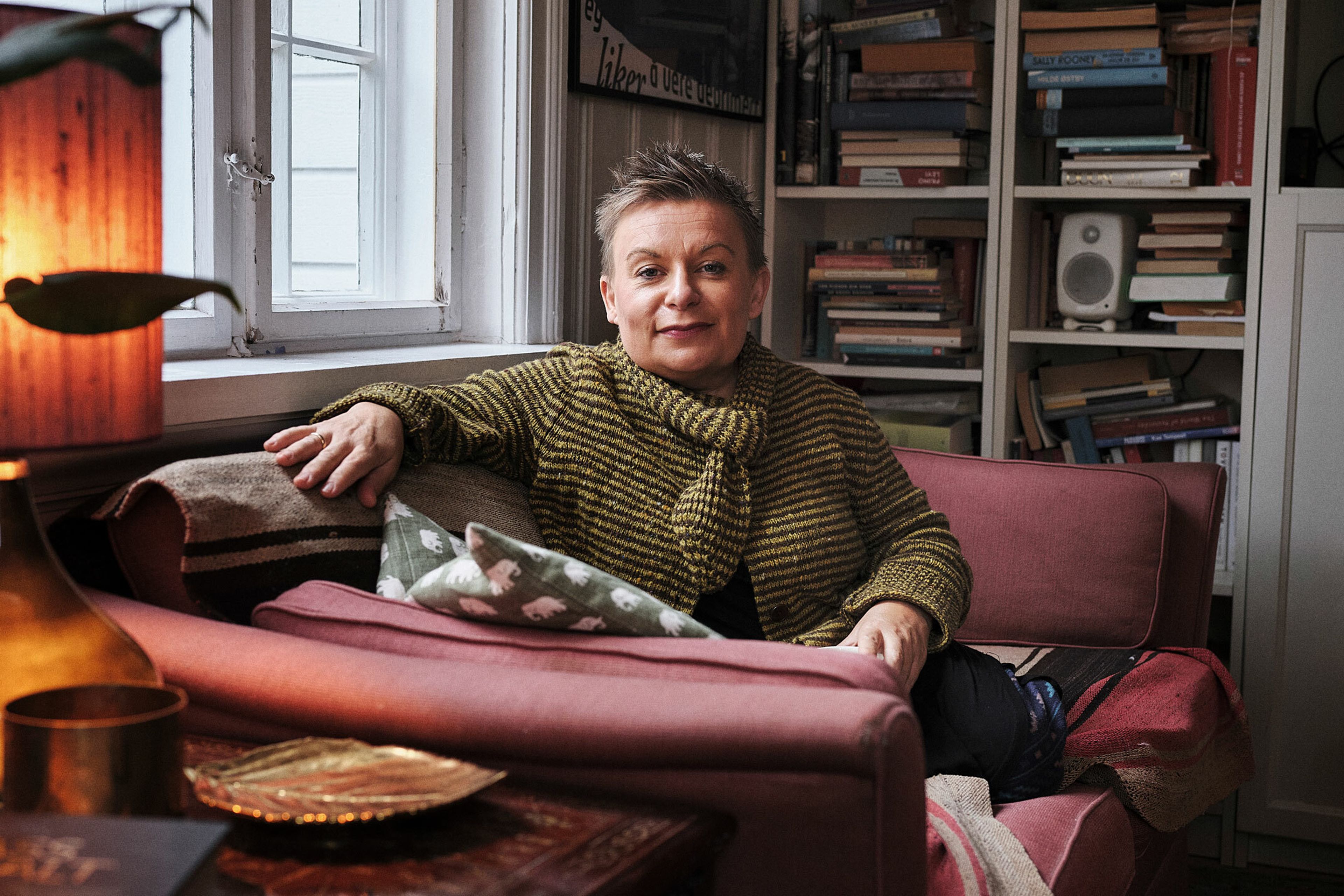 Kjersti Horn sitter i sofaen hjemme. Hun har på seg en gul strikket genser.