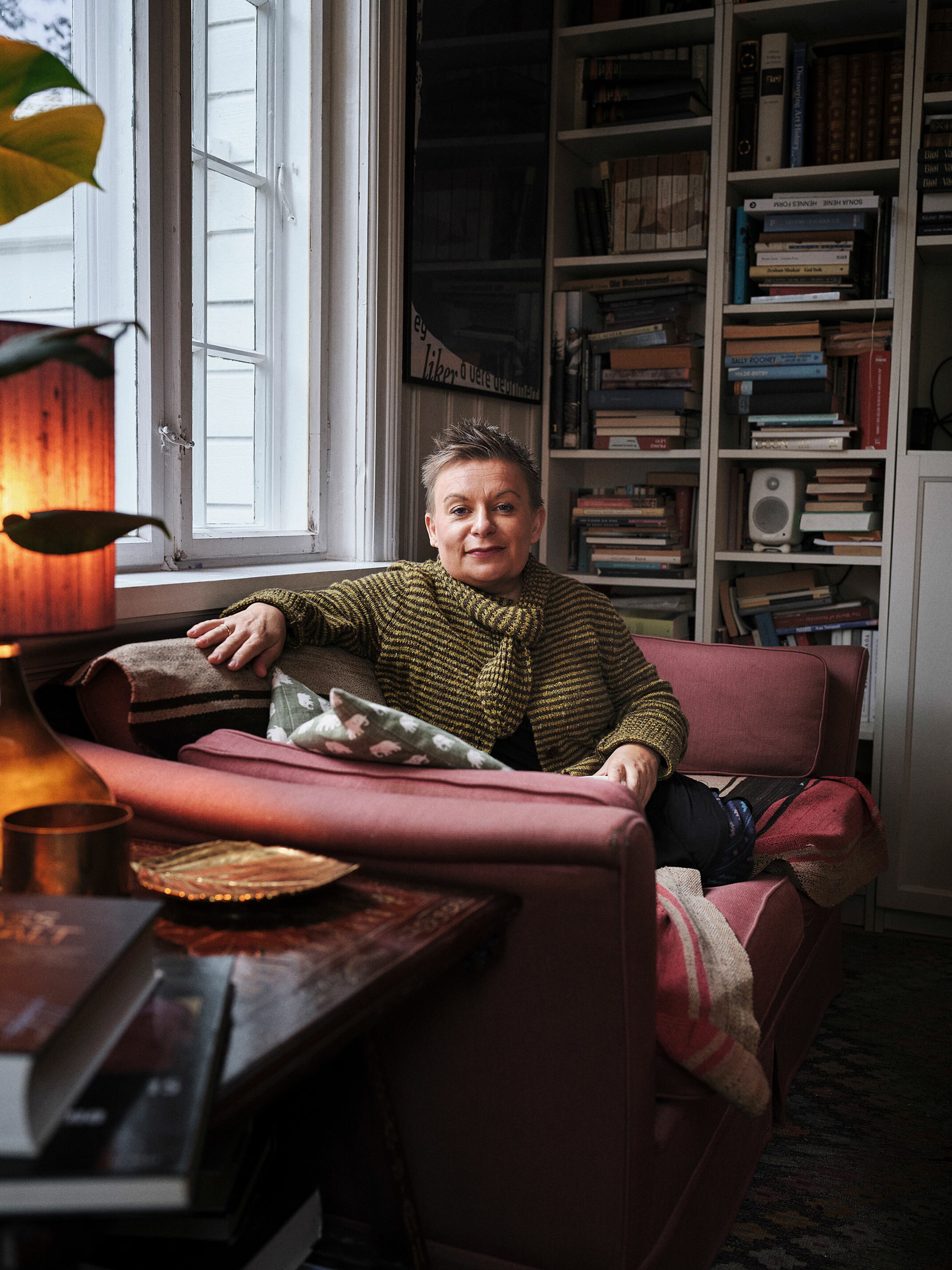 Kjersti Horn sitter i sofaen hjemme. Hun har på seg en gul strikket genser.