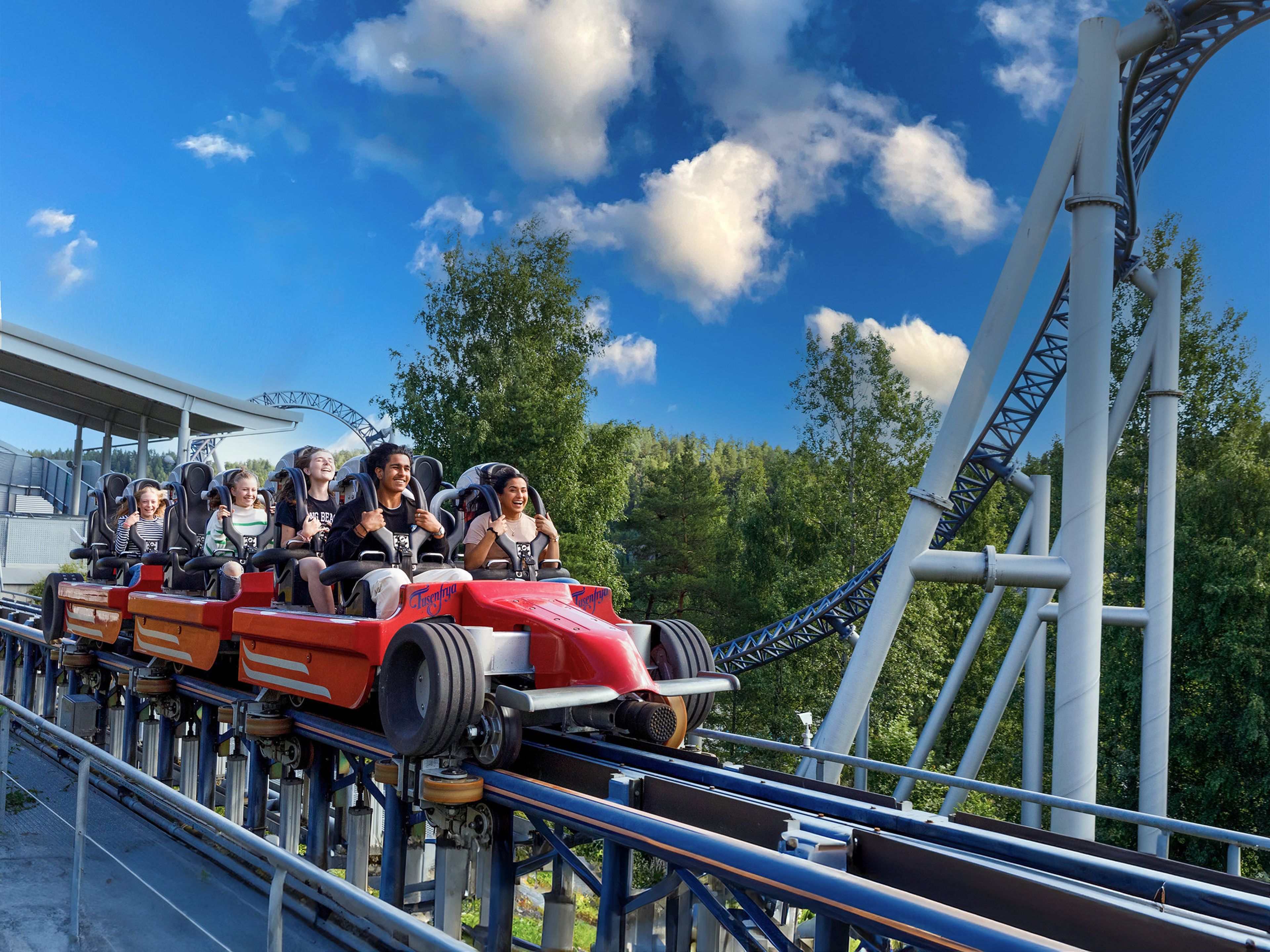 Det sitter flere glade ungdom i speedmonster-karusellen og smiler. Karusellen har akkurat stoppet.