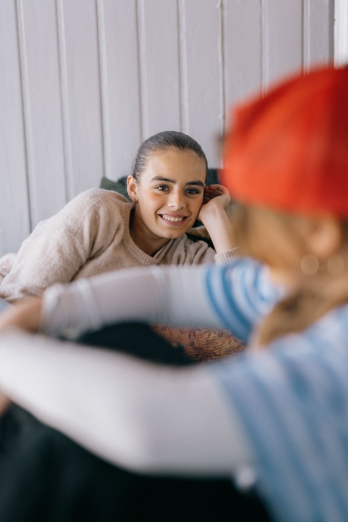 Ei jente ligger og lener seg på hånda. Hun smiler bredt.