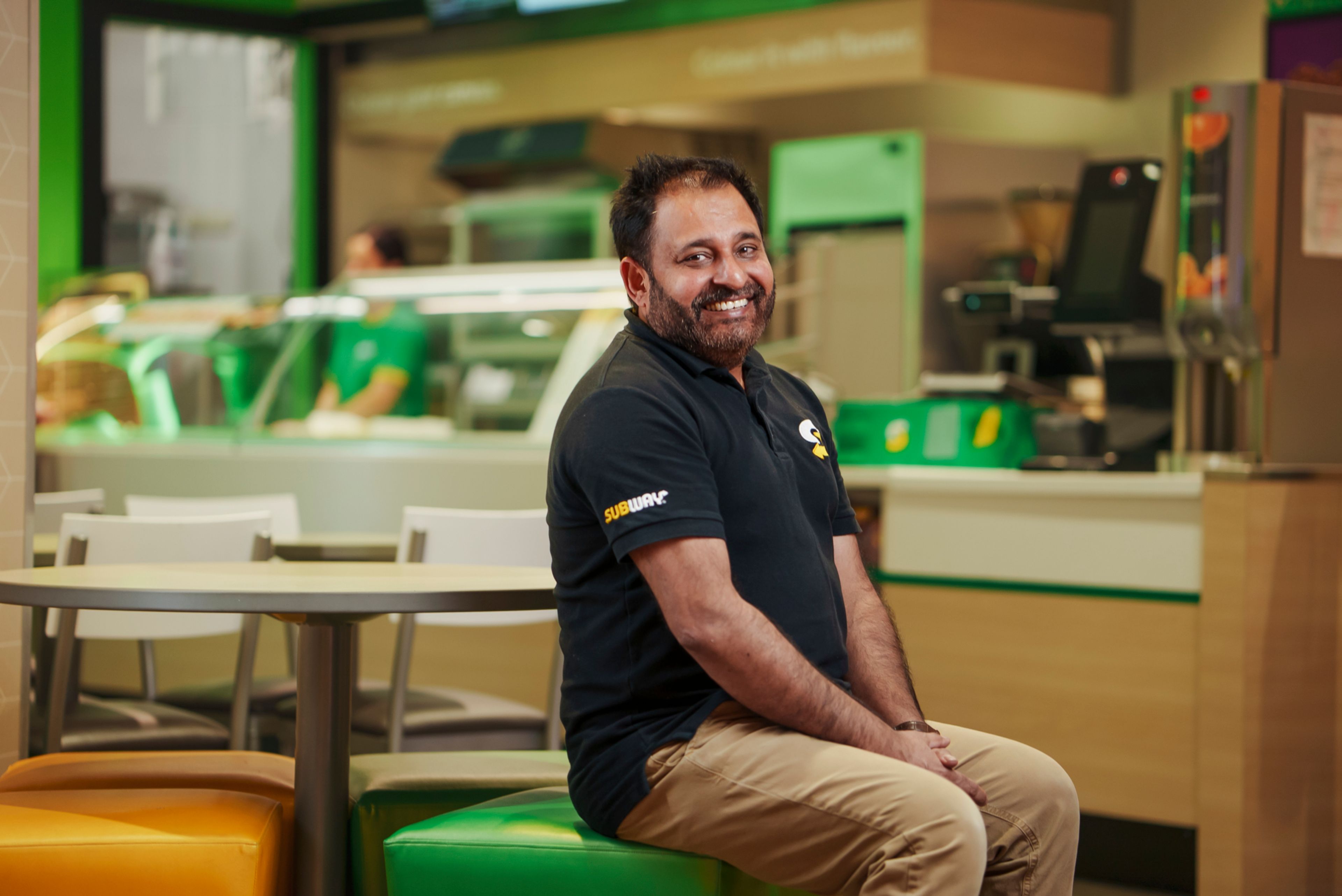 Iftikhar Malik sitter på en av stolene i Subway-restauranten sin.