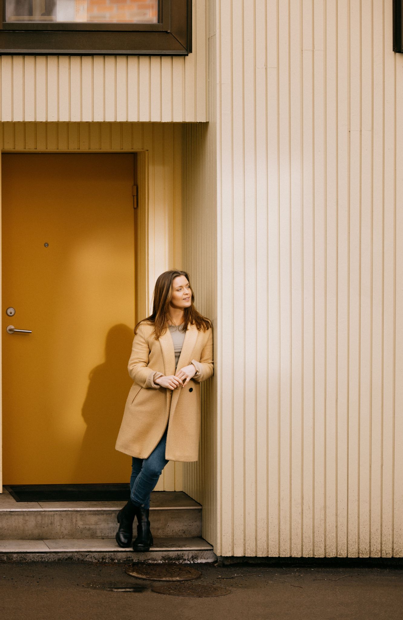Portrett av Maria Tøsse som lener seg til en husvegg.