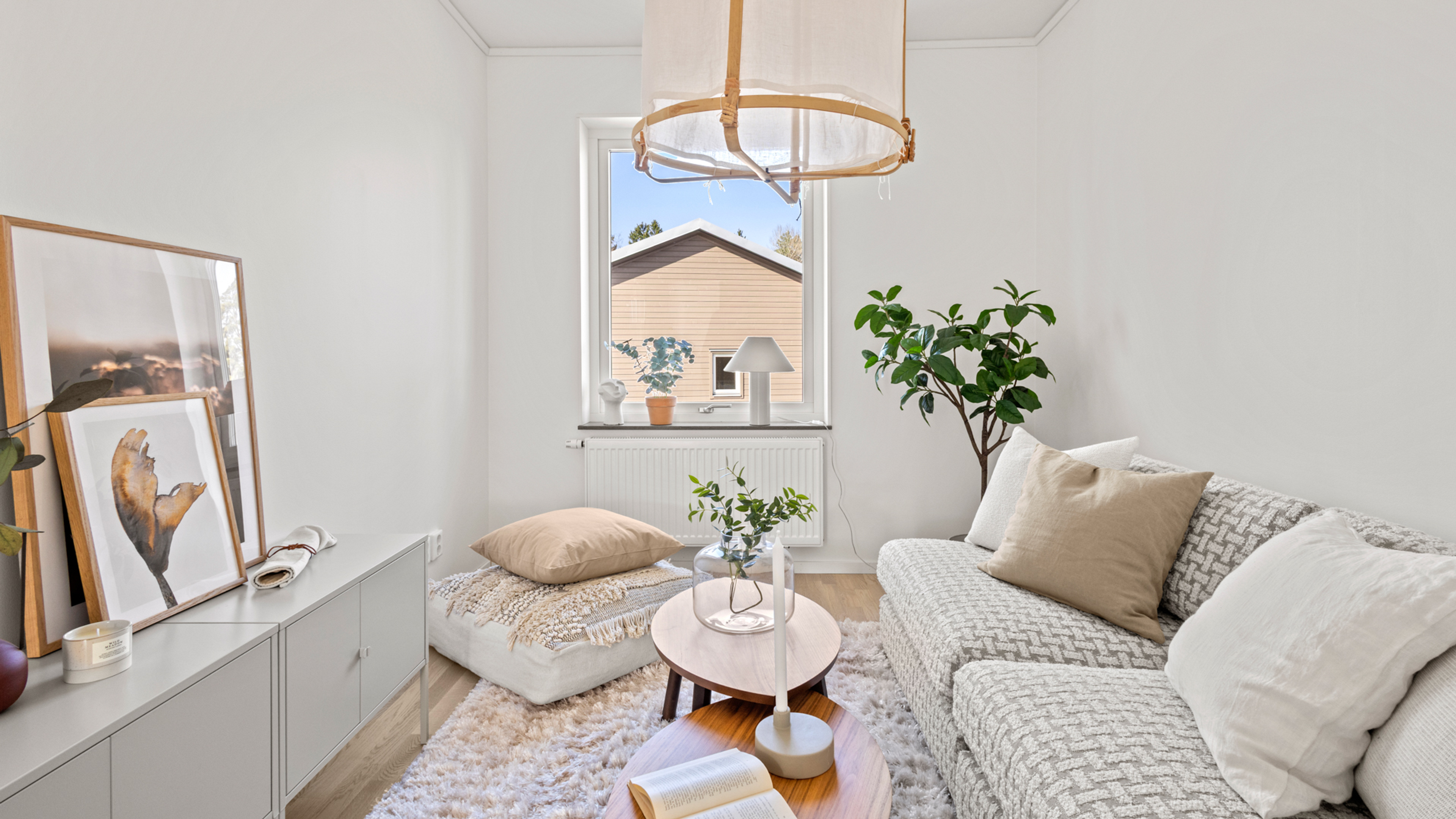 Bild på ett rum med soffa till höger och TV bänk med TV till vänster samt fönster rakt fram