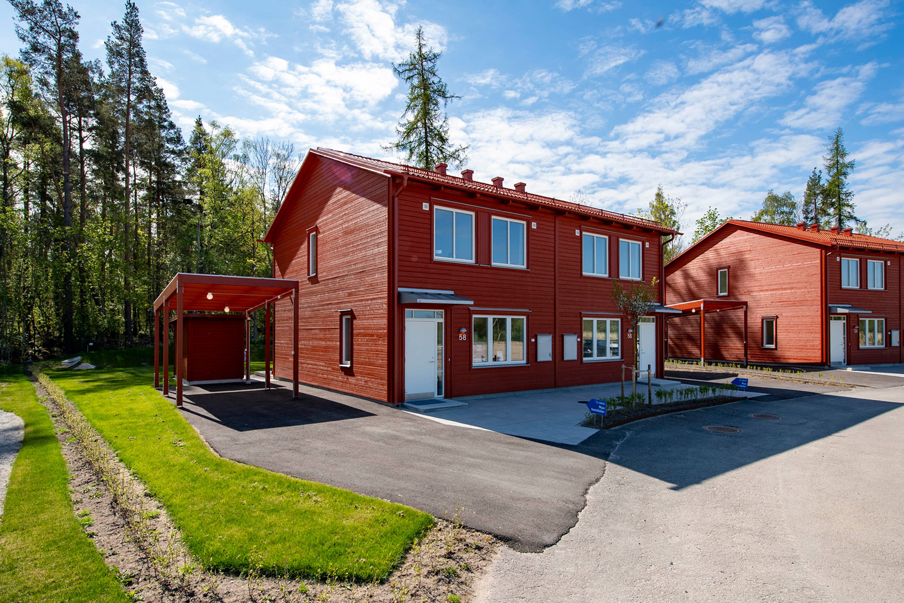 Exteriör rött parhus med vit ytterdörr uppfart och carport