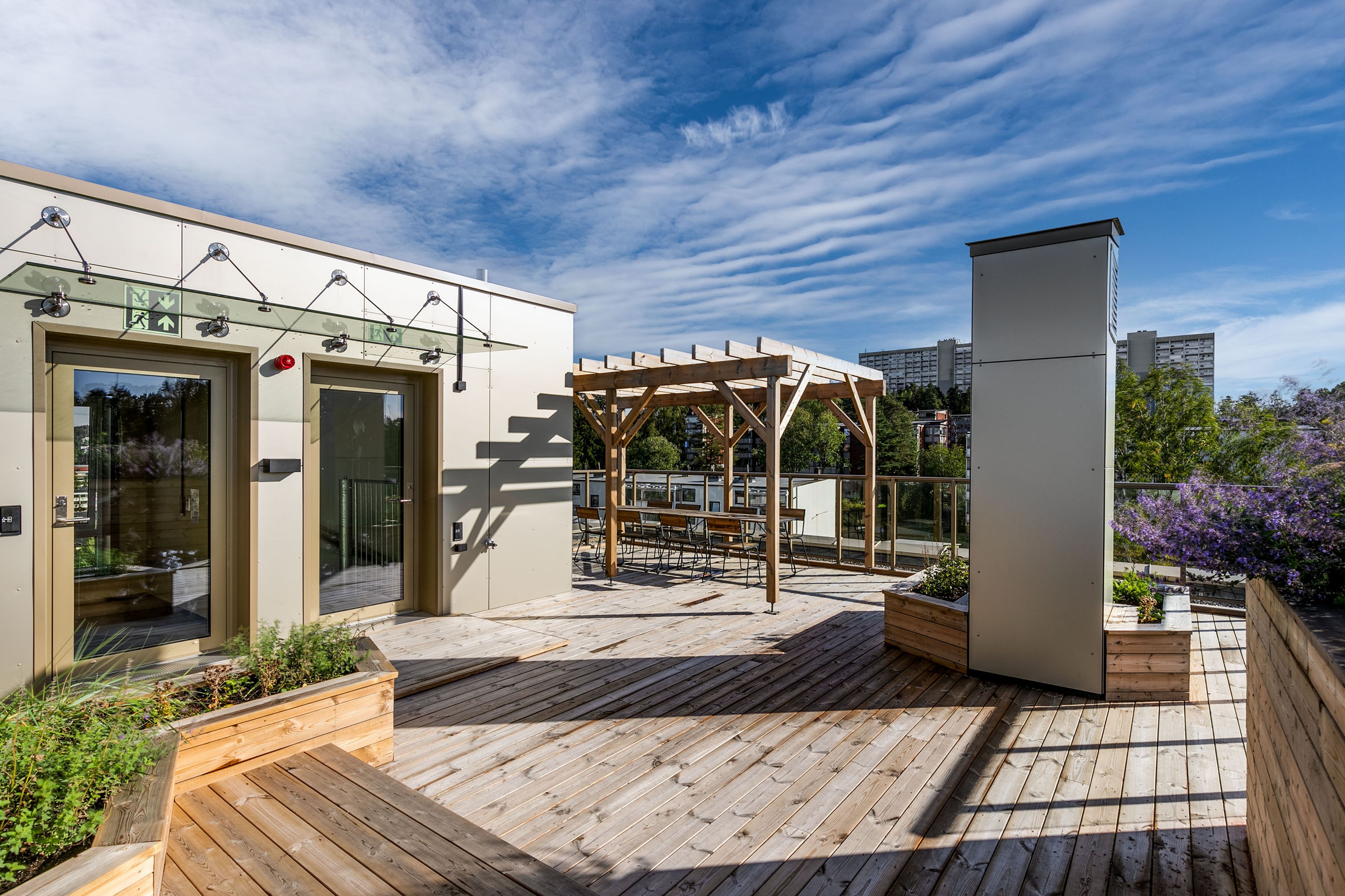 Takterrasse med pergola og sitteplasser i sommersola på MIDT i Lørenskog.