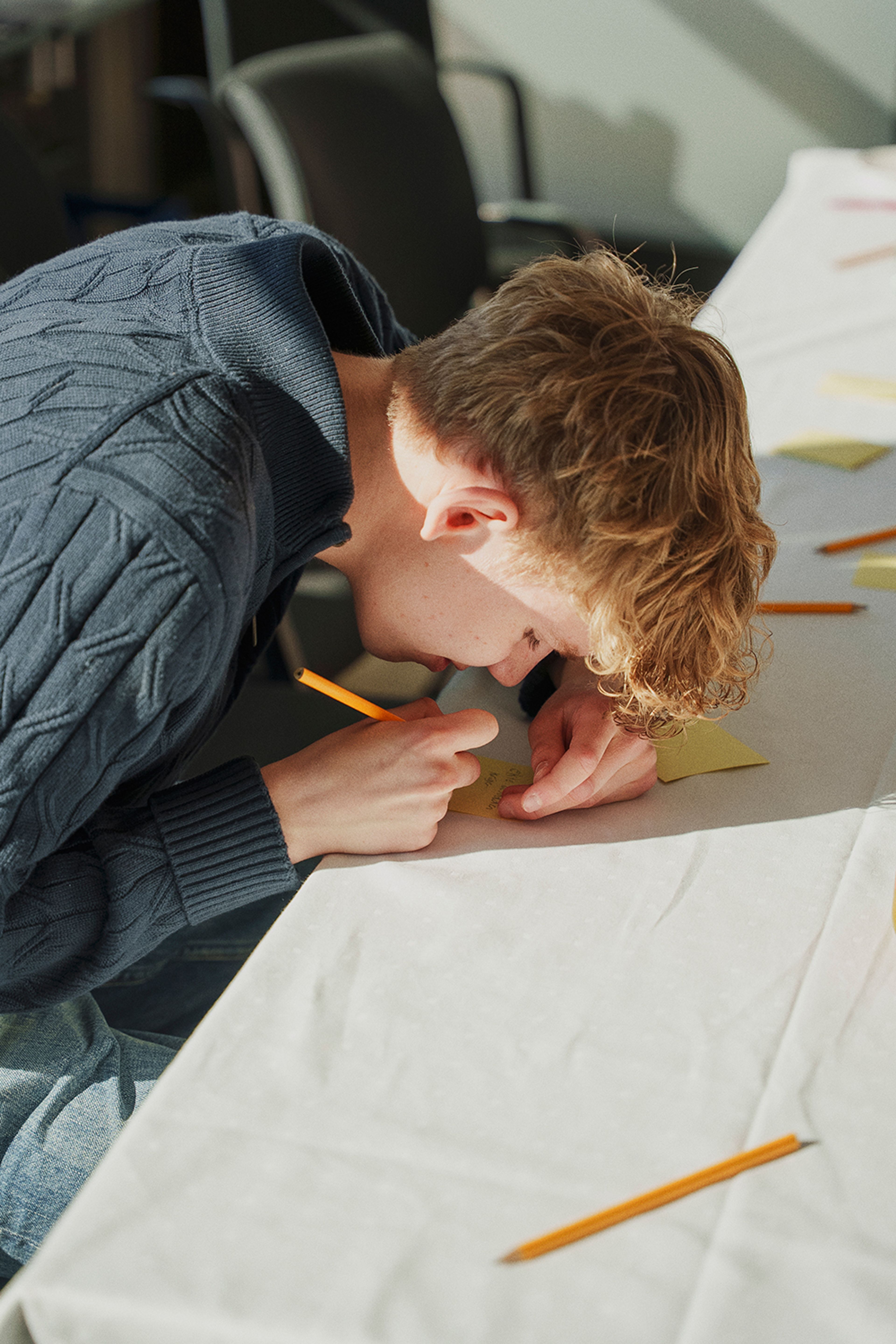 Frederik Honne Frøysa skriver noe på en lapp på workshopen.