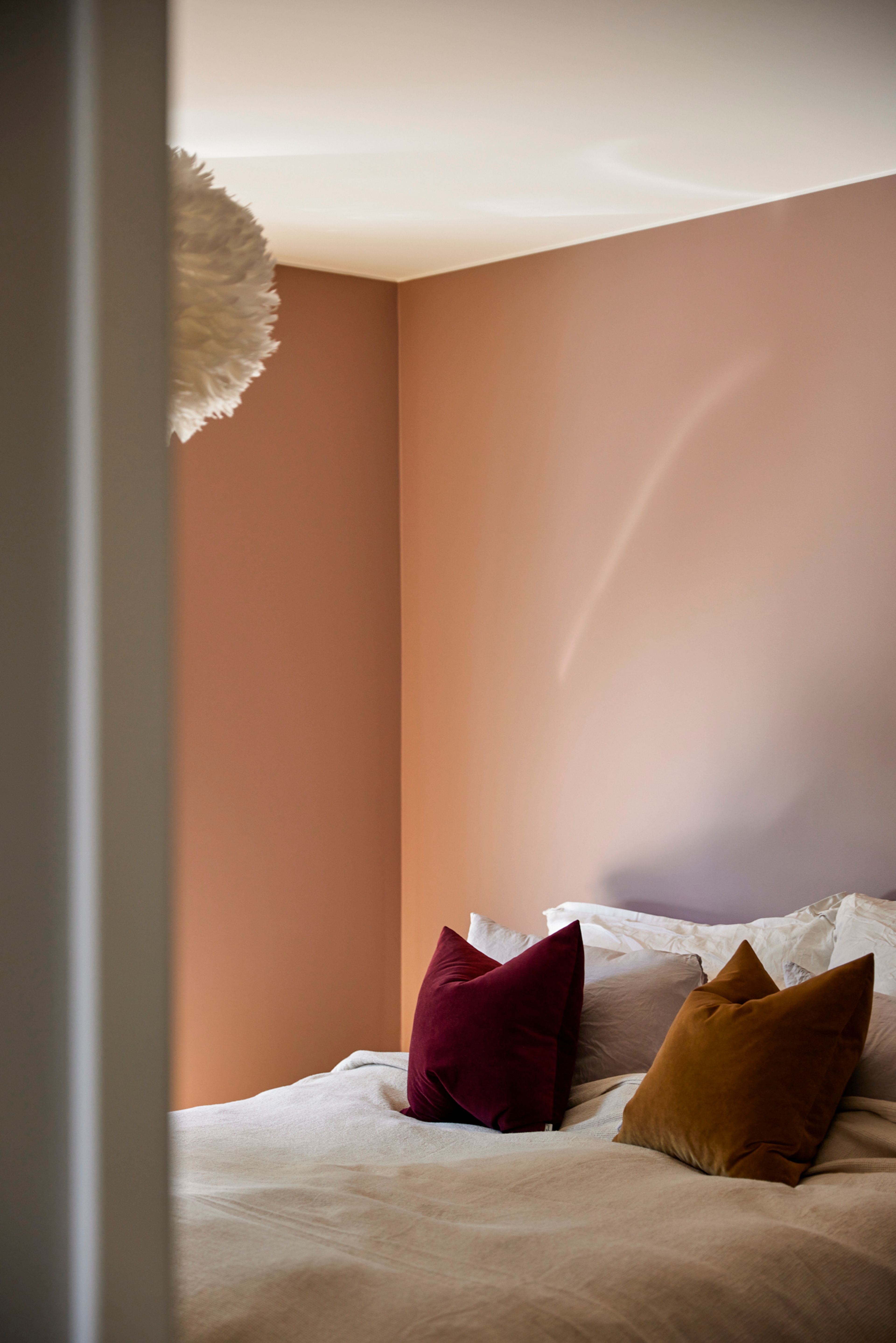 Rosa soverom med en dobbeltseng i bakgrunnen med en hvit taklampe hengende over