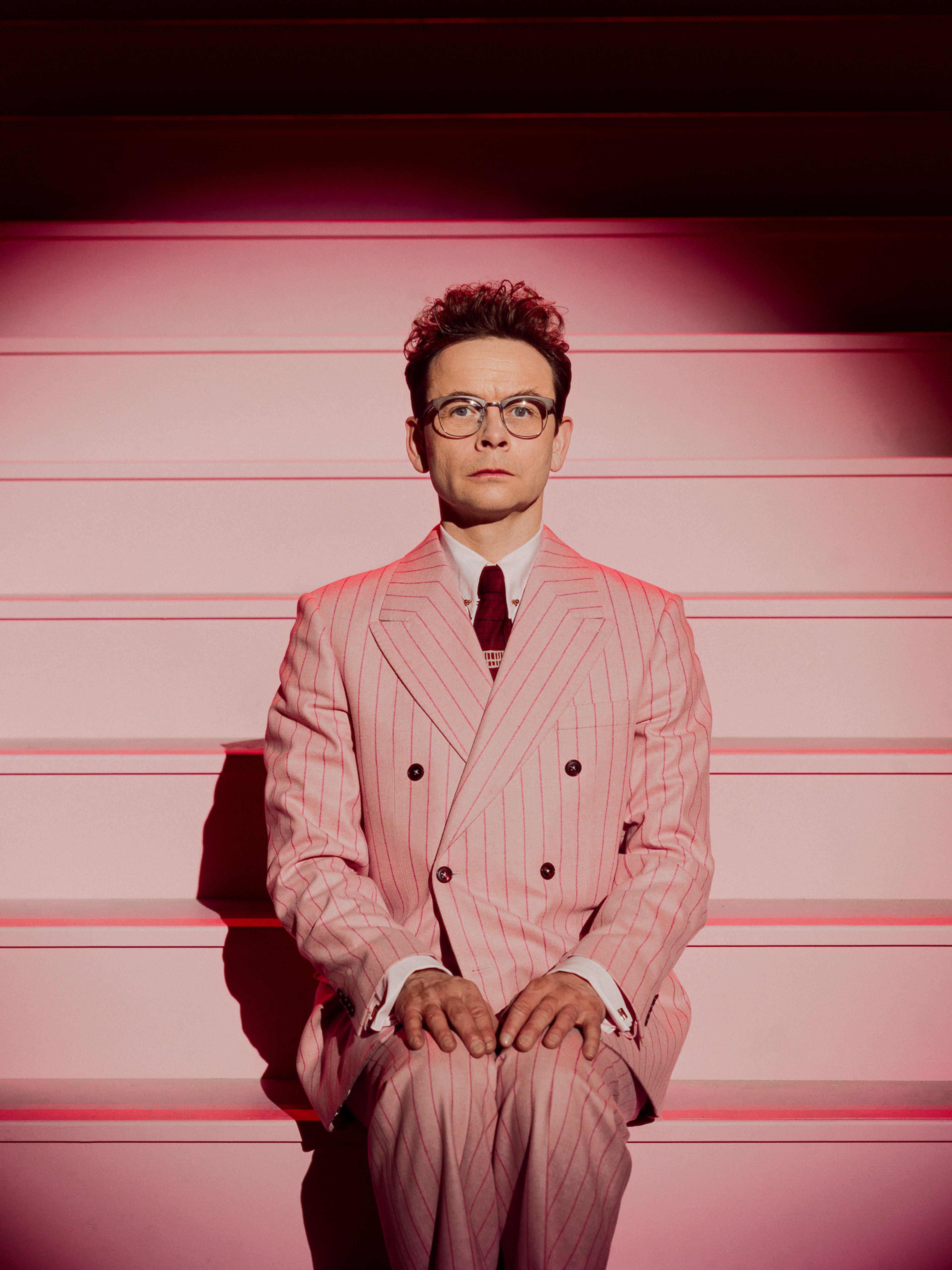 Foto av Jan Gunnar Røise i en rosa dress. Han sitter i en trapp på nationaltheateret.