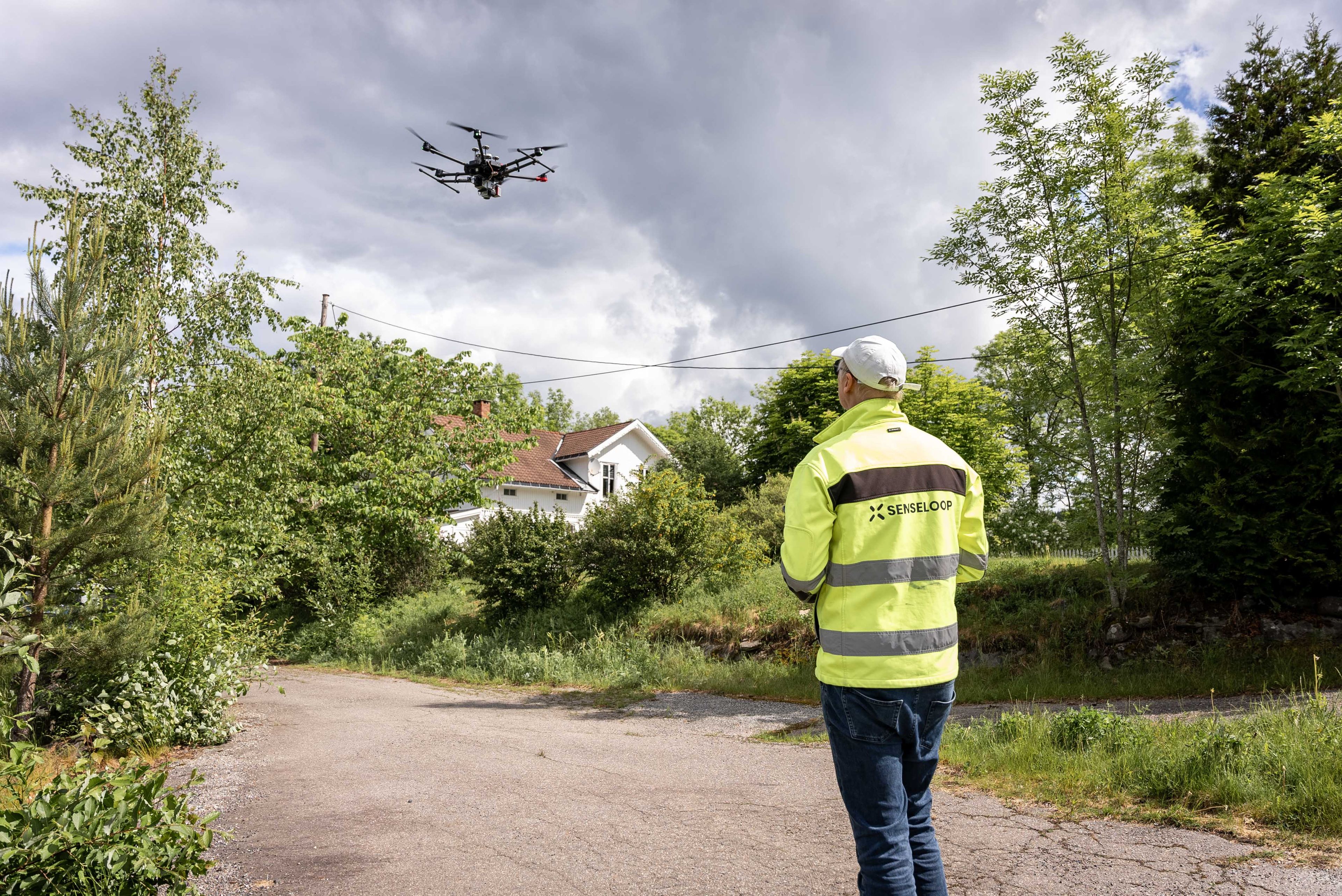 En droneoperatør styrer en drone i lufta.