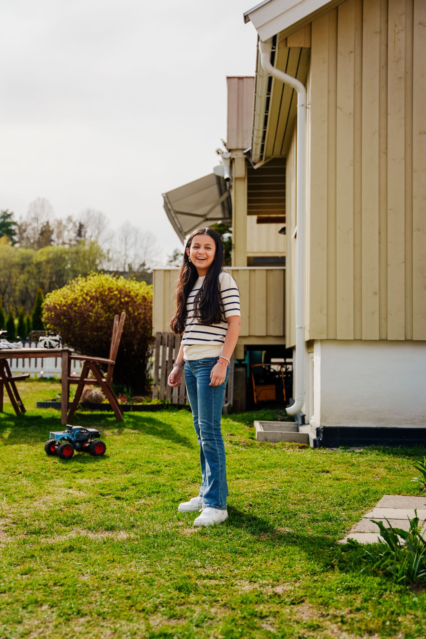 Melissa står i hagen foran det gule rekkehuset.